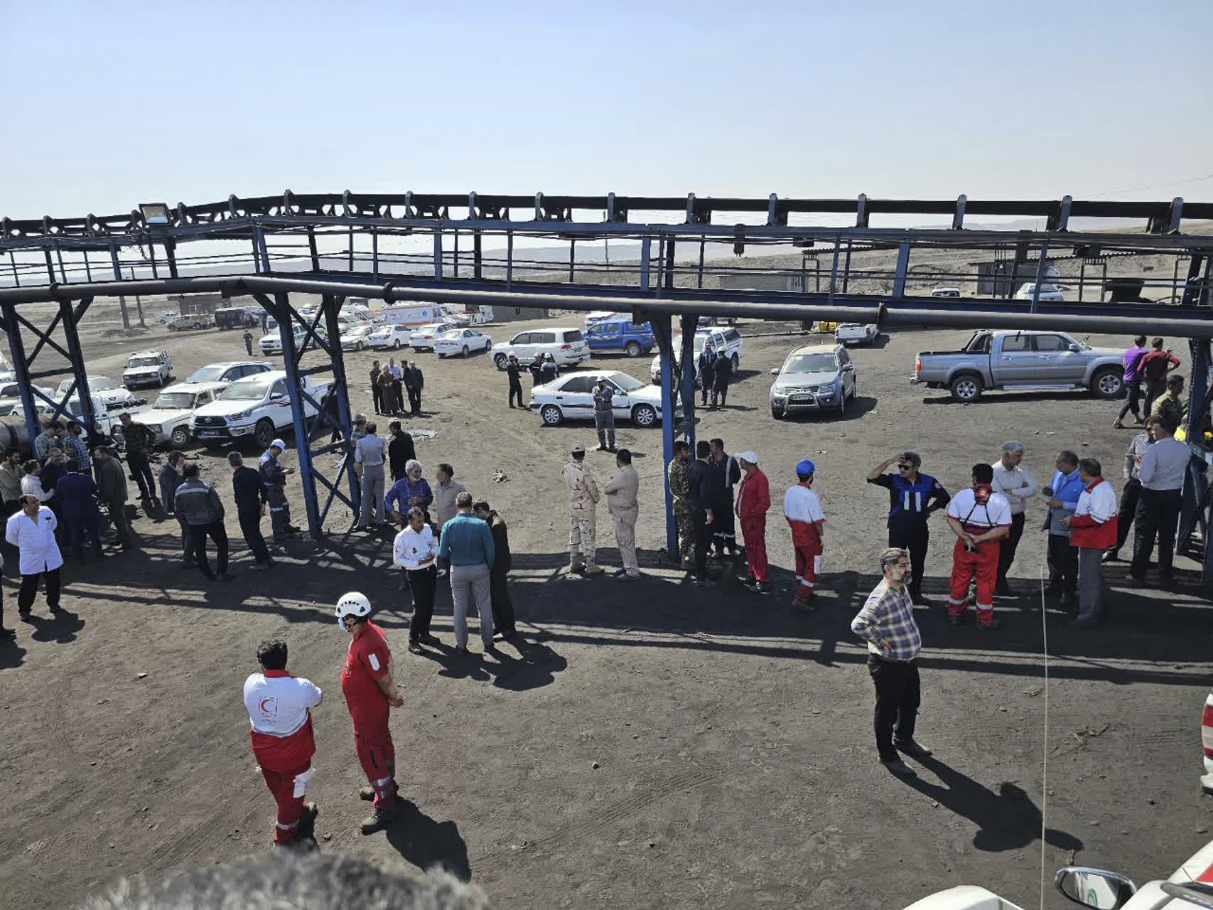 In this photo released by Iranian Red Crescent Society, rescue personnel, police officers and some other people gather around the site of a coal mine where methane leak sparked an explosion on Saturday, in Tabas, some 335 miles (540 kilometers) southeast of the capital Tehran, Iran, Sunday, Sept. 22, 2024. (Iranian Red Crescent Society, via AP)