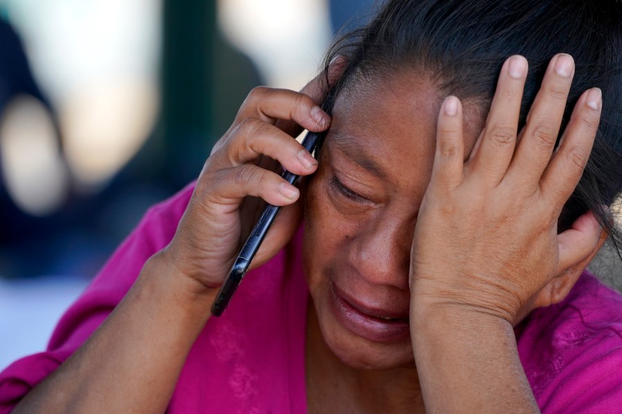 FILE - A migrant woman cries as she talks on a cellphone at a park after she and a large group of deportees from the U.S. were pushed by Mexican authorities off an area they had been staying after their expulsion, Saturday, March 20, 2021, in Reynosa, Mexico. (AP Photo/Julio Cortez)