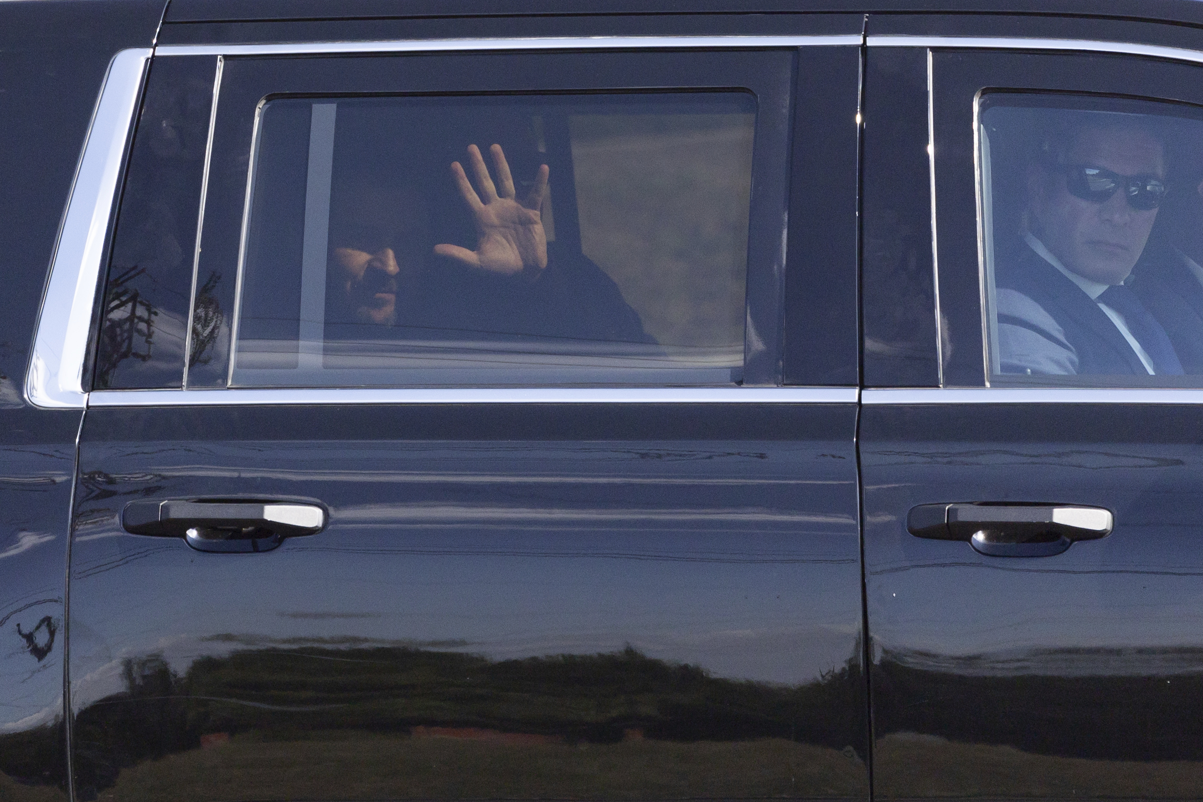 Ukrainian President Volodymyr Zelenskyy waves from the back seat of a U.S. Secret Service vehicle as his motorcade departs the Wilkes-Barre/Scranton International Airport in Pittston Township, Pa. en route to the Scranton Army Ammunition Plant in Scranton, Pa. on Sunday, Sept. 22, 2024. (Christopher Dolan/The Times-Tribune via AP)