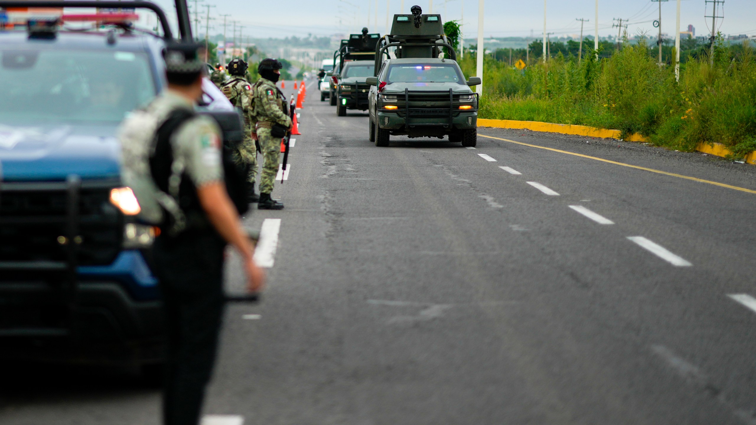 Soldiers traveling in armored vehicles patrol an area where a body was found lying on the side of a road, in Culiacan, Sinaloa state, Mexico, Saturday, Sept. 21, 2024. (AP Photo/Eduardo Verdugo)