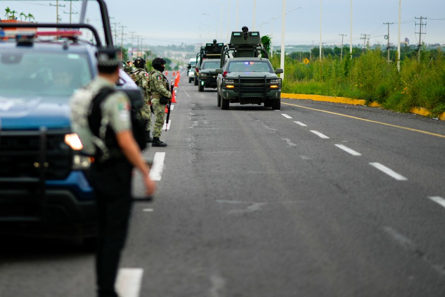 Soldiers traveling in armored vehicles patrol an area where a body was found lying on the side of a road, in Culiacan, Sinaloa state, Mexico, Saturday, Sept. 21, 2024. (AP Photo/Eduardo Verdugo)