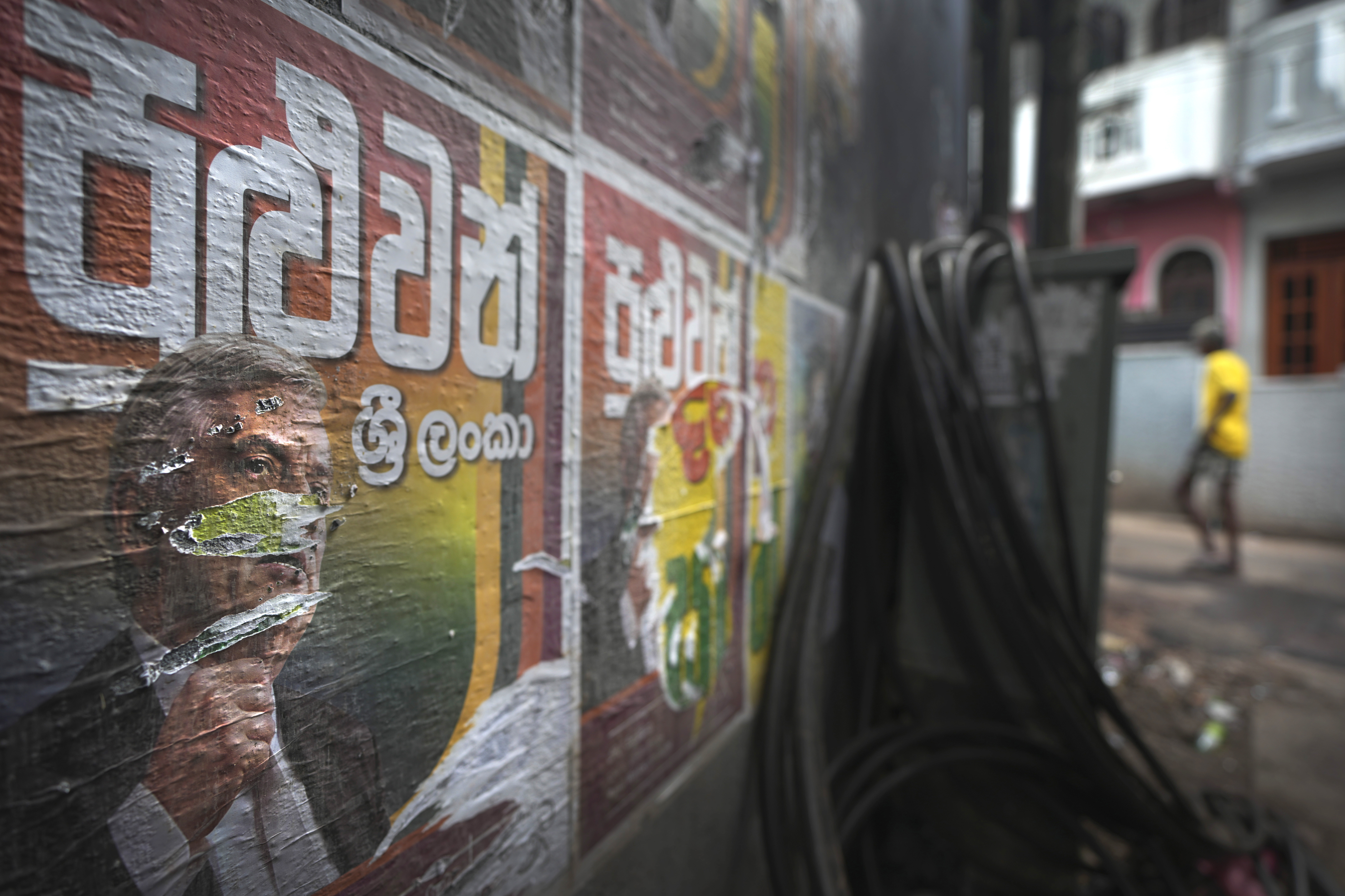 A man walks past torn election posters of President Ranil Wickremesinghe at a street in Colombo, Sri Lanka, Sunday, Sept. 22, 2024.(AP Photo/Rajesh Kumar Singh)