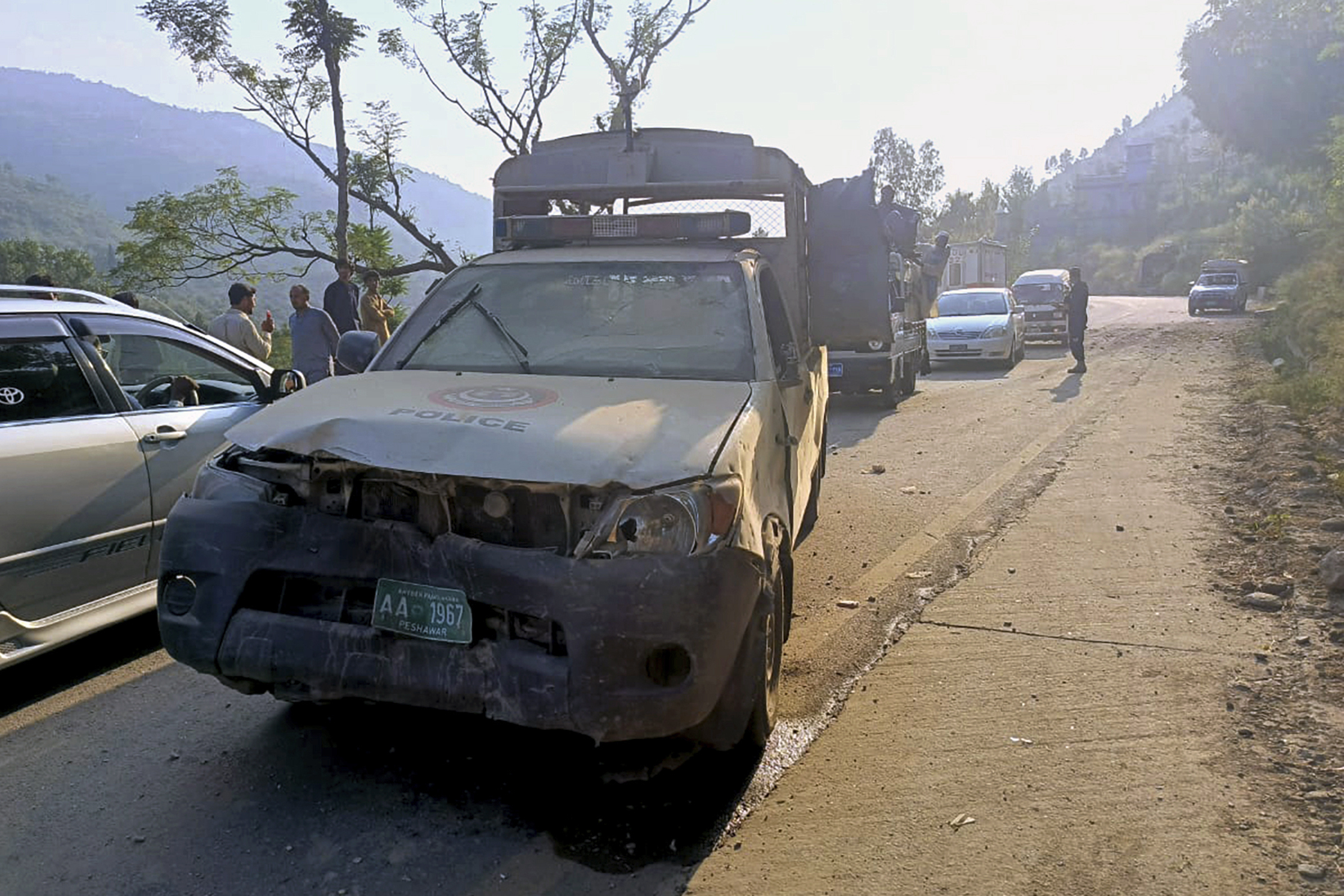 Vehicles drive past a damaged police vehicle, foreground, which was escorting a convoy of foreign diplomats, at the site of a fatal bomb explosion on a road near Malam Jabba, a tourist area in Pakistan's Khyber Pakhtunkhwa province, Sunday, Sept. 22, 2024. (AP Photo/Sherin Zada)