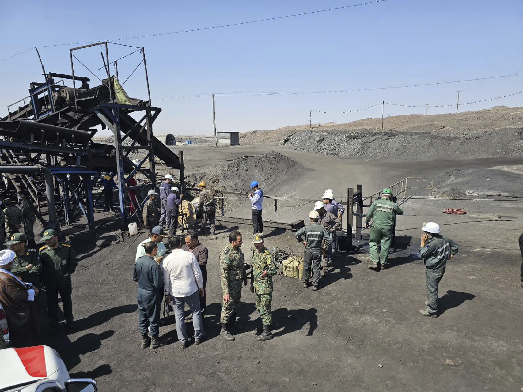 In this photo released by Iranian Red Crescent Society, miners and police officers gather around the site of a coal mine where methane leak sparked an explosion on Saturday, in Tabas, some 335 miles (540 kilometers) southeast of the capital Tehran, Iran, Sunday, Sept. 22, 2024. (Iranian Red Crescent Society, via AP)