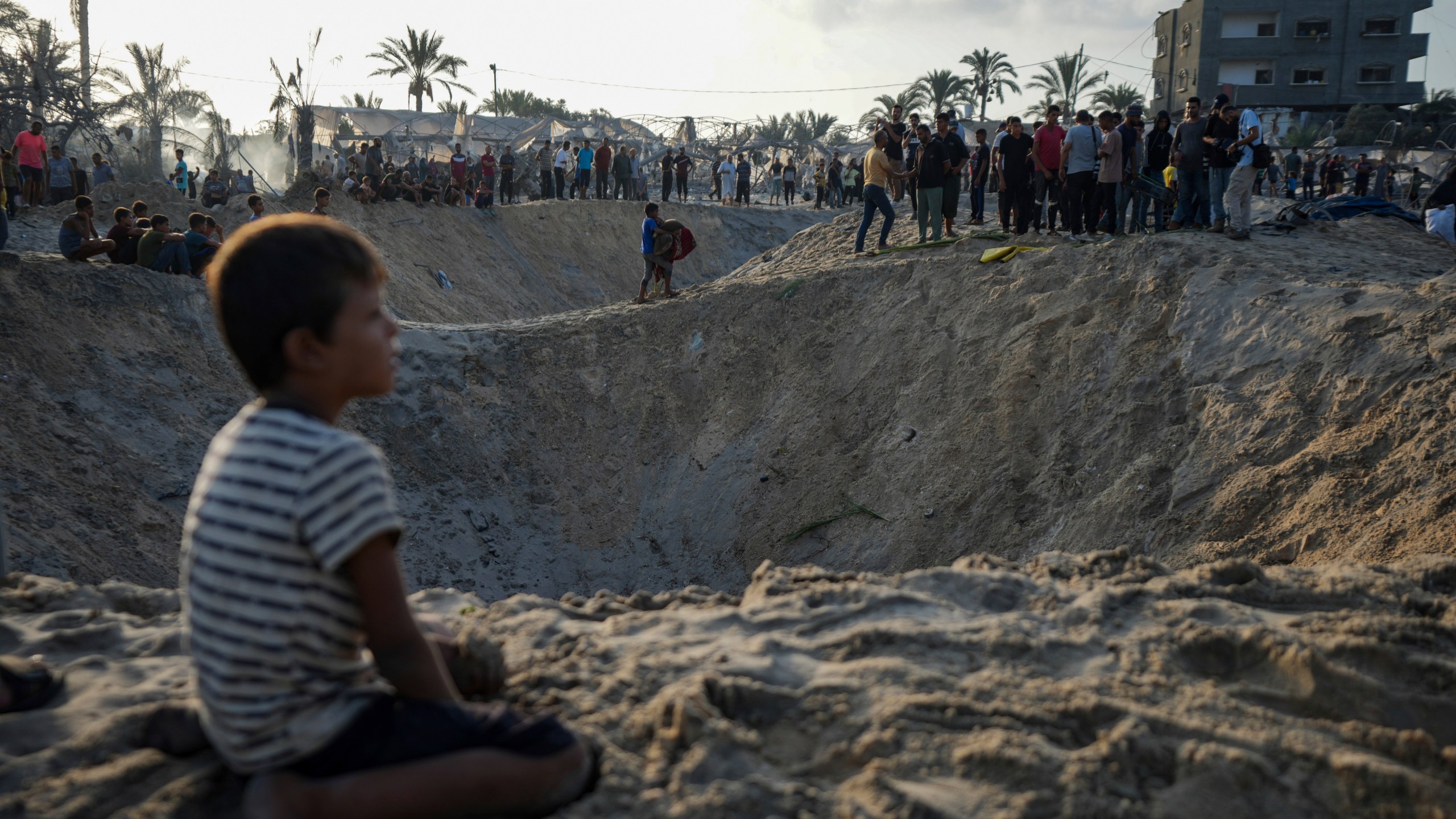 FILE - Palestinians look at the destruction after an Israeli airstrike on a crowded tent camp housing Palestinians displaced by the war in Muwasi, Gaza Strip, Sept. 10, 2024. (AP Photo/Abdel Kareem Hana, file)