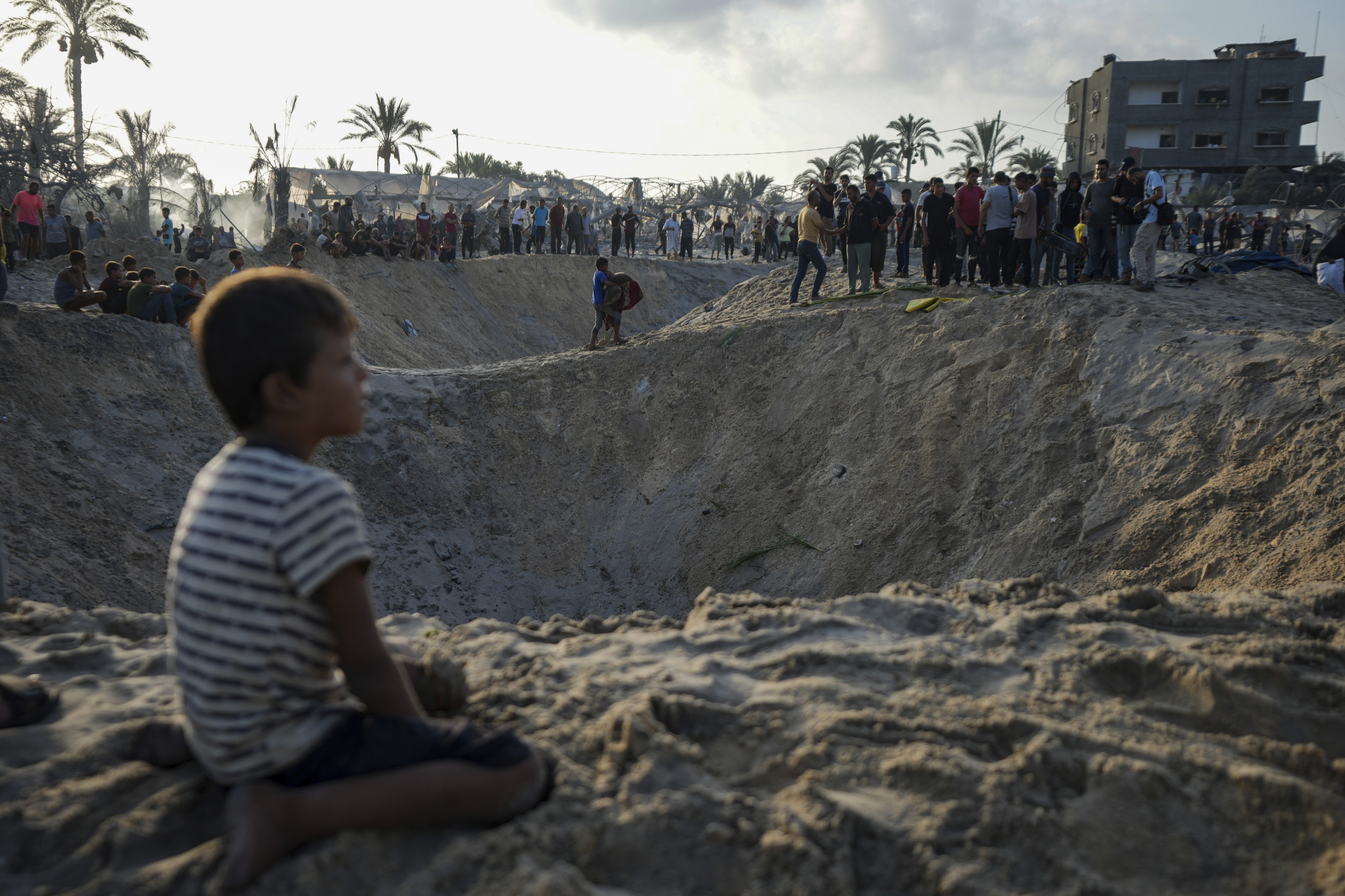 FILE - Palestinians look at the destruction after an Israeli airstrike on a crowded tent camp housing Palestinians displaced by the war in Muwasi, Gaza Strip, Sept. 10, 2024. (AP Photo/Abdel Kareem Hana, file)