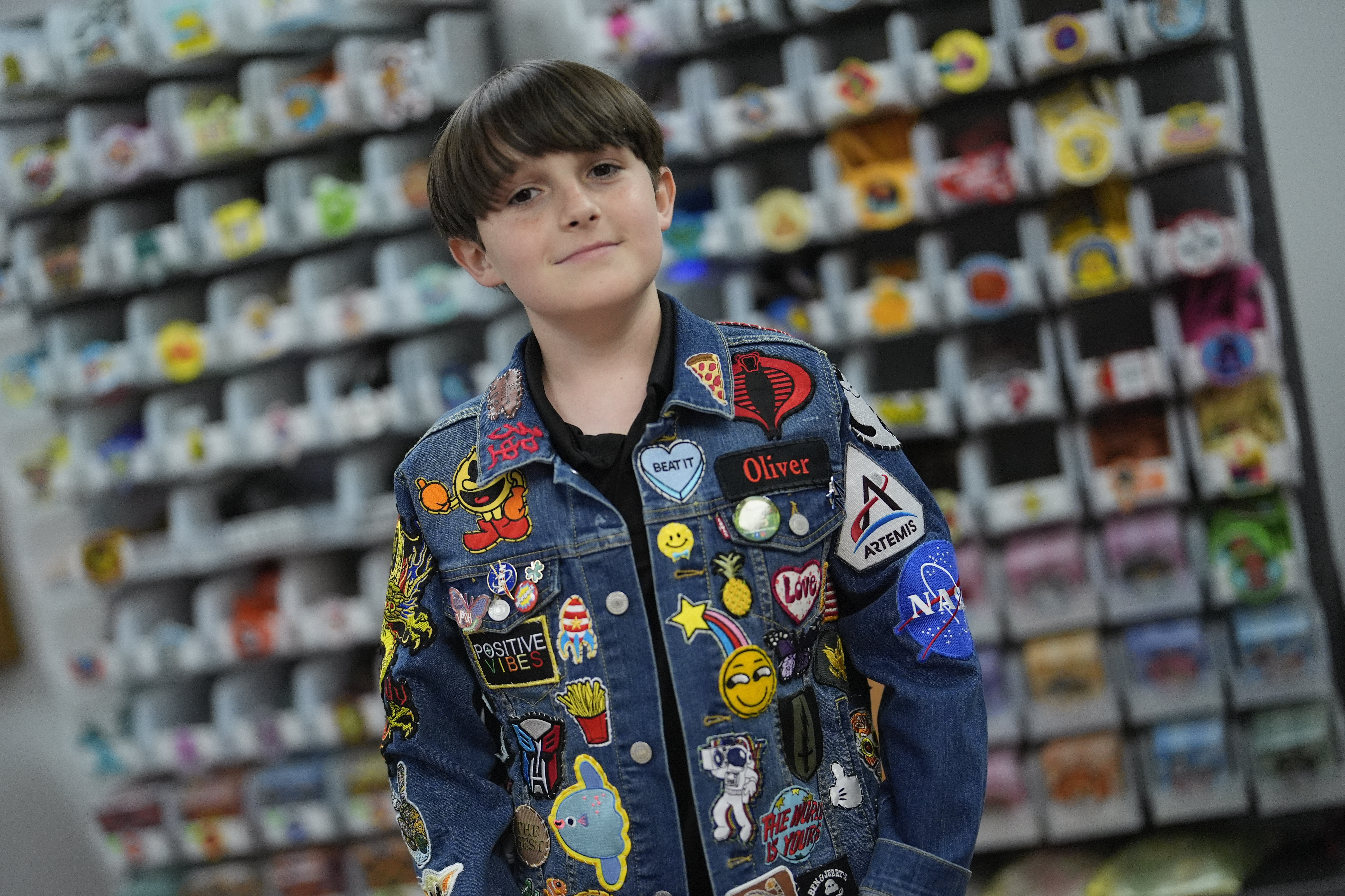 Oliver Burkhardt, 13, stands in front of trays of patches inside the offices of the Oliver Patch Project, Wednesday, Sept. 4, 2024, in Miami. (AP Photo/Rebecca Blackwell)