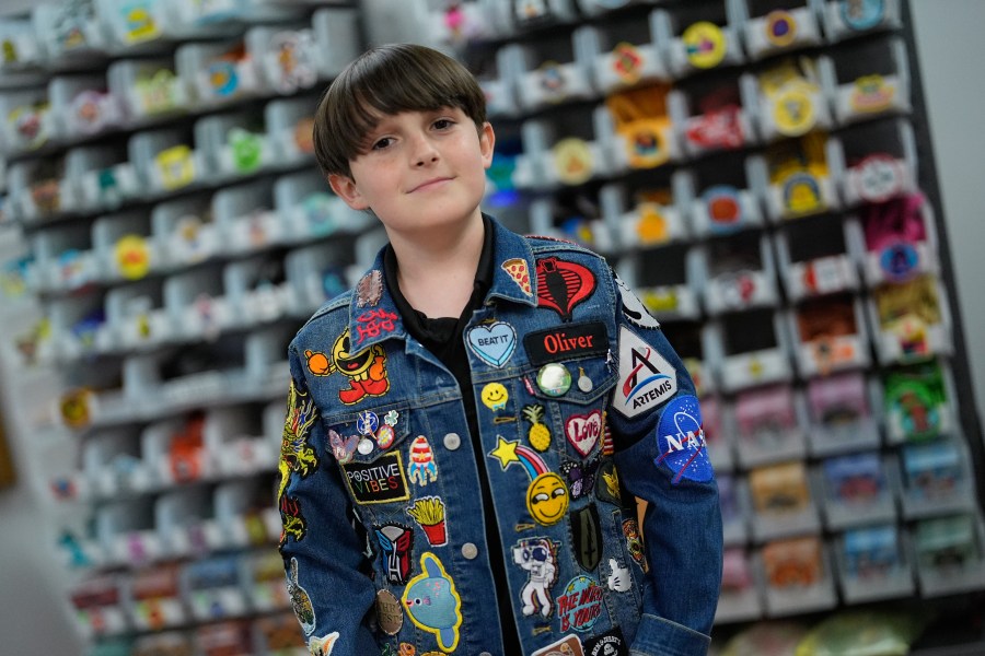 Oliver Burkhardt, 13, stands in front of trays of patches inside the offices of the Oliver Patch Project, Wednesday, Sept. 4, 2024, in Miami. (AP Photo/Rebecca Blackwell)