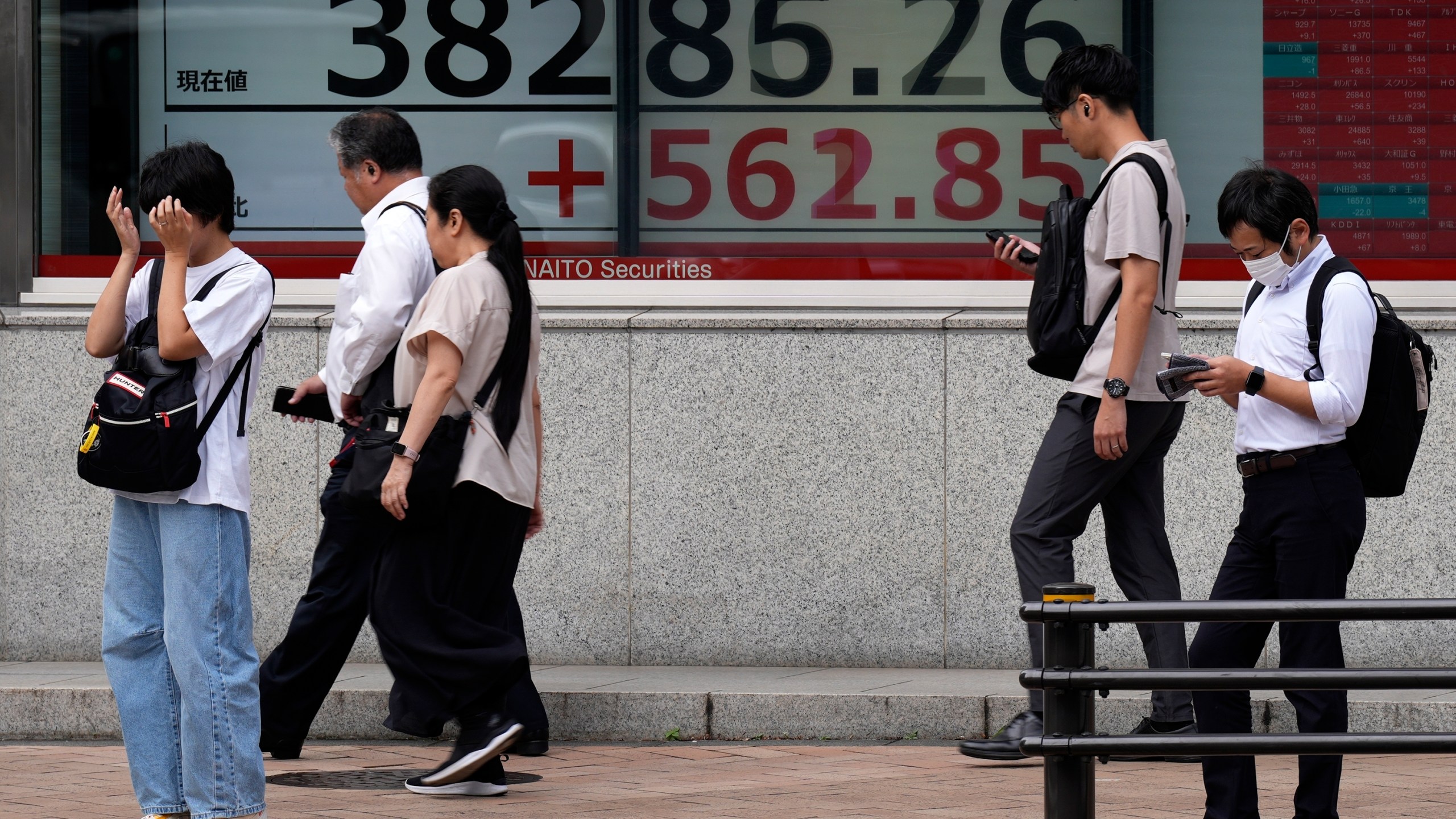 People walk in front of an electronic stock board showing Japan's Nikkei index at a securities firm Tuesday, Sept. 24, 2024, in Tokyo. (AP Photo/Eugene Hoshiko)