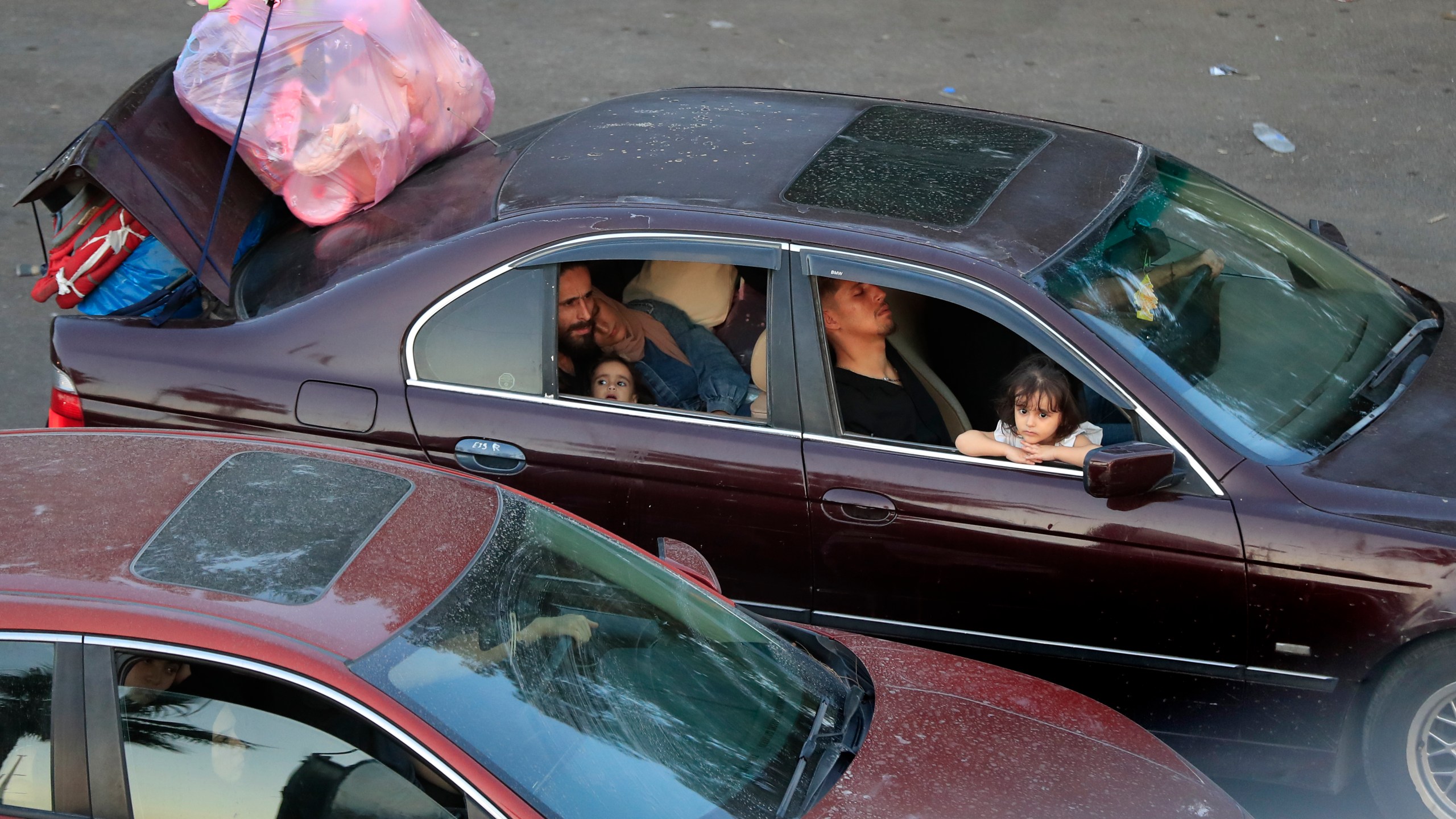 Lebanese citizens who fled the southern villages amid ongoing Israeli airstrikes Monday, sit in their cars at a highway that links to Beirut city, in the southern port city of Sidon, Lebanon, Tuesday, Sept. 24, 2024. (AP Photo/Mohammed Zaatari)