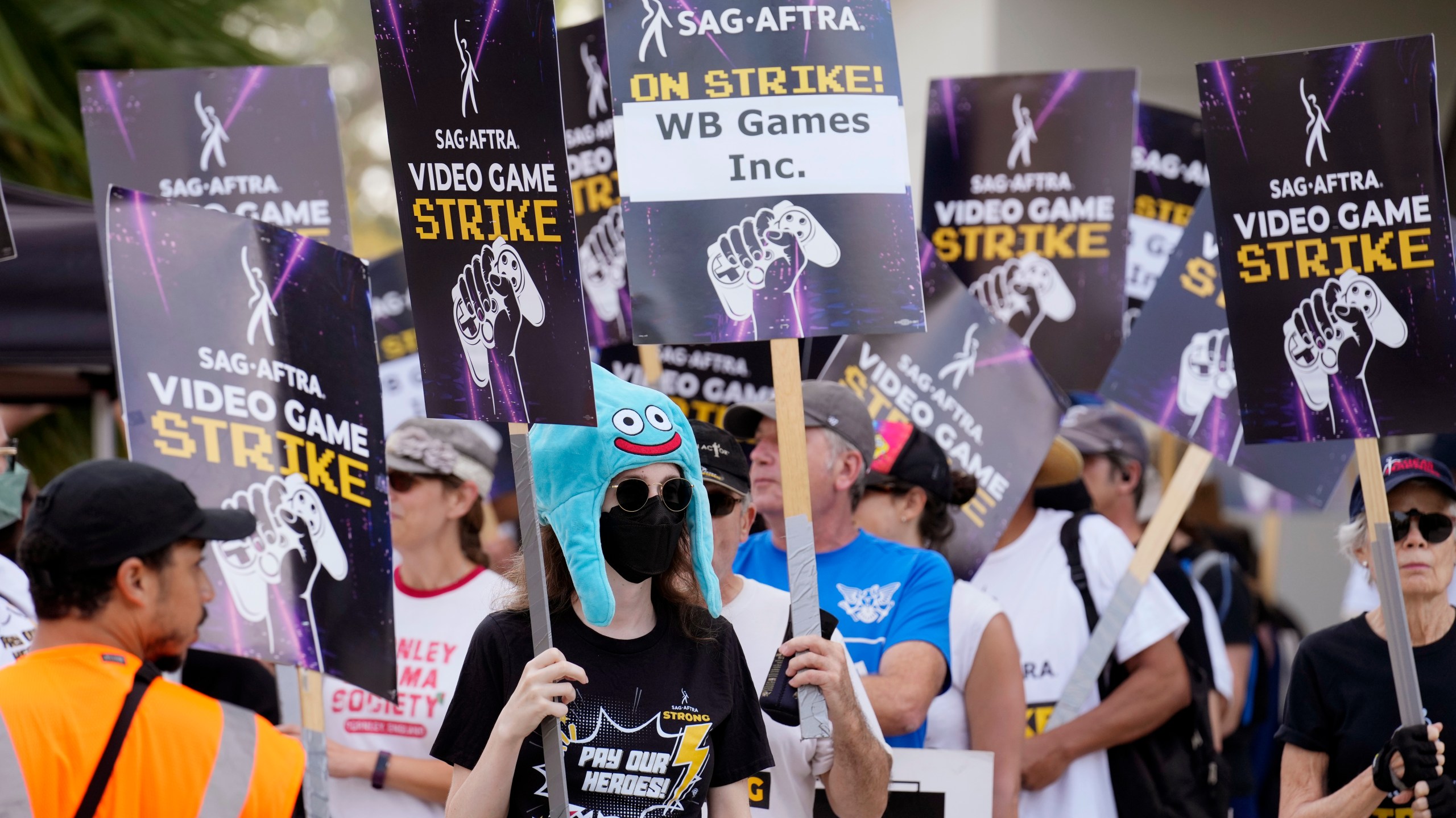 Actor Sena Bryer, second from left, joins other demonstrators in a SAG-AFTRA video game actor strike picket line outside Warner Bros. Studios on Wednesday, Aug. 28, 2024, in Burbank, Calif. (AP Photo/Chris Pizzello)