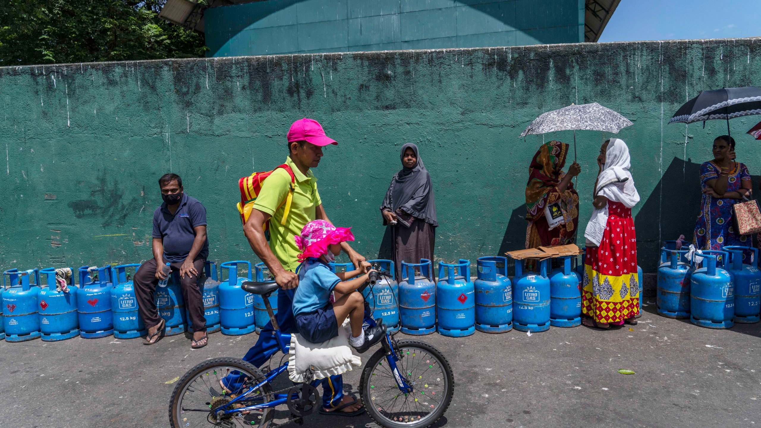 FILE - People wait in a queue with empty cylinders to buy domestic gas at a distribution center, in Colombo, Sri Lanka, on July 12, 2022. (AP Photo/Rafiq Maqbool, File)