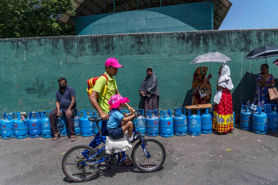 FILE - People wait in a queue with empty cylinders to buy domestic gas at a distribution center, in Colombo, Sri Lanka, on July 12, 2022. (AP Photo/Rafiq Maqbool, File)