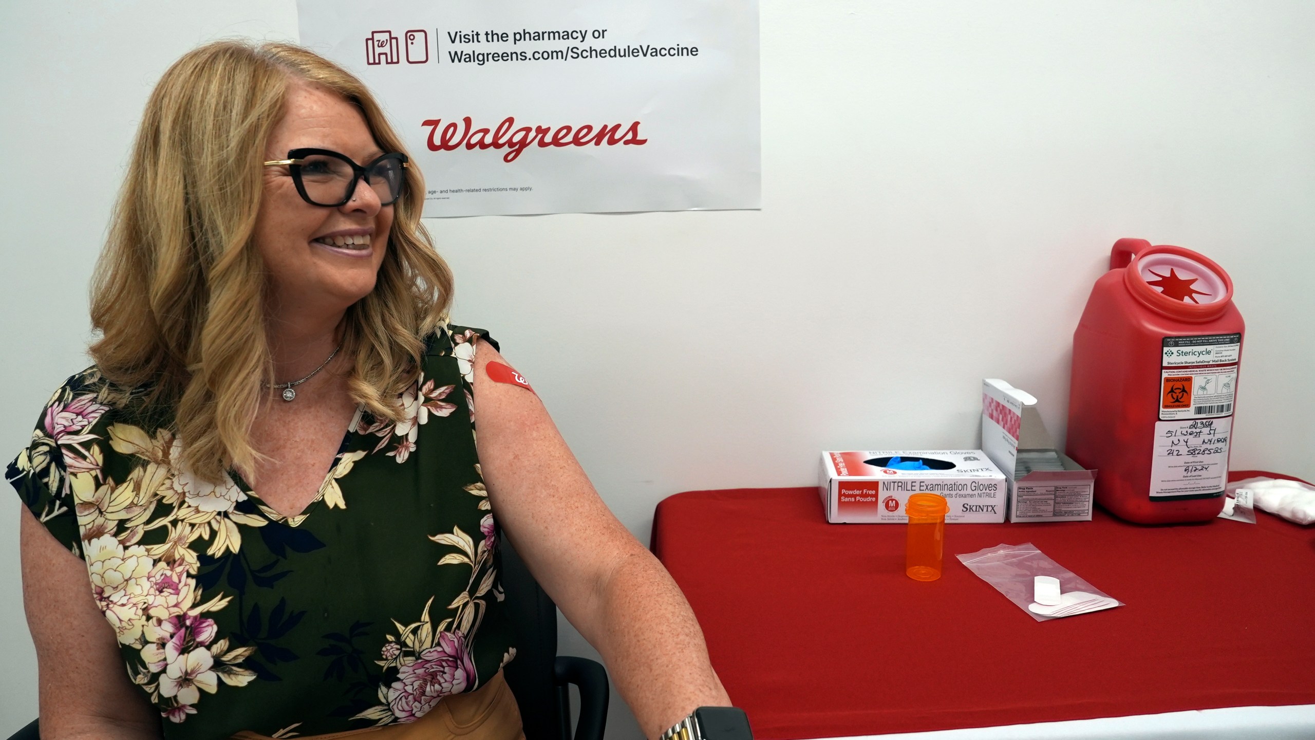 Kelly Vazquez sits down after receiving COVID-19 and flu shots at a pharmacy in New York, on Tuesday, Sept. 24, 2024. (AP Photo/Mary Conlon)