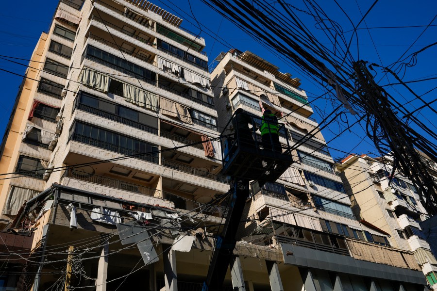 Municipality workers remove power cables in front of damaged buildings at the site of an Israeli airstrike in Beirut's southern suburb, Thursday, Sept. 26, 2024. (AP Photo/Hassan Ammar)