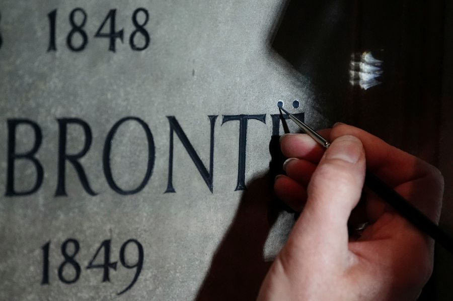 Conservator Lucy Ackland adds the finishing touches to the memorial to Charlotte, Emily and Anne Bronte at Poets' Corner in Westminster Abbey in London, England, Thursday Sept. 26, 2024. (Aaron Chown/PA via AP)