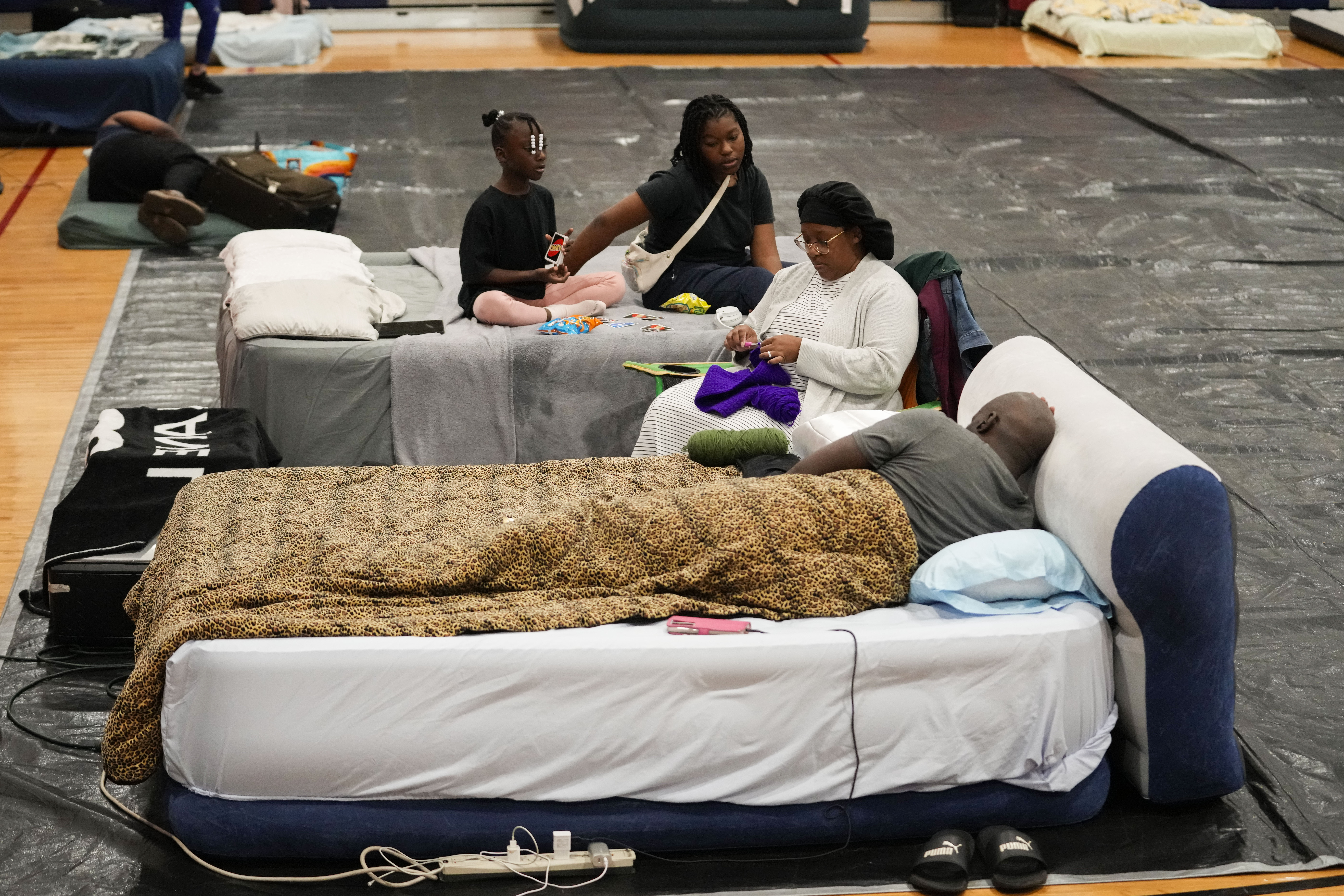 Sharonda and Victor Davis, of Tallahassee, sit with their children Victoria background left, and Amaya, background right, inside a hurricane evacuation shelter at Fairview Middle School, ahead of Hurricane Helene, expected to make landfall here today, in Leon County, Fla., Thursday, Sept. 26, 2024. (AP Photo/Gerald Herbert)