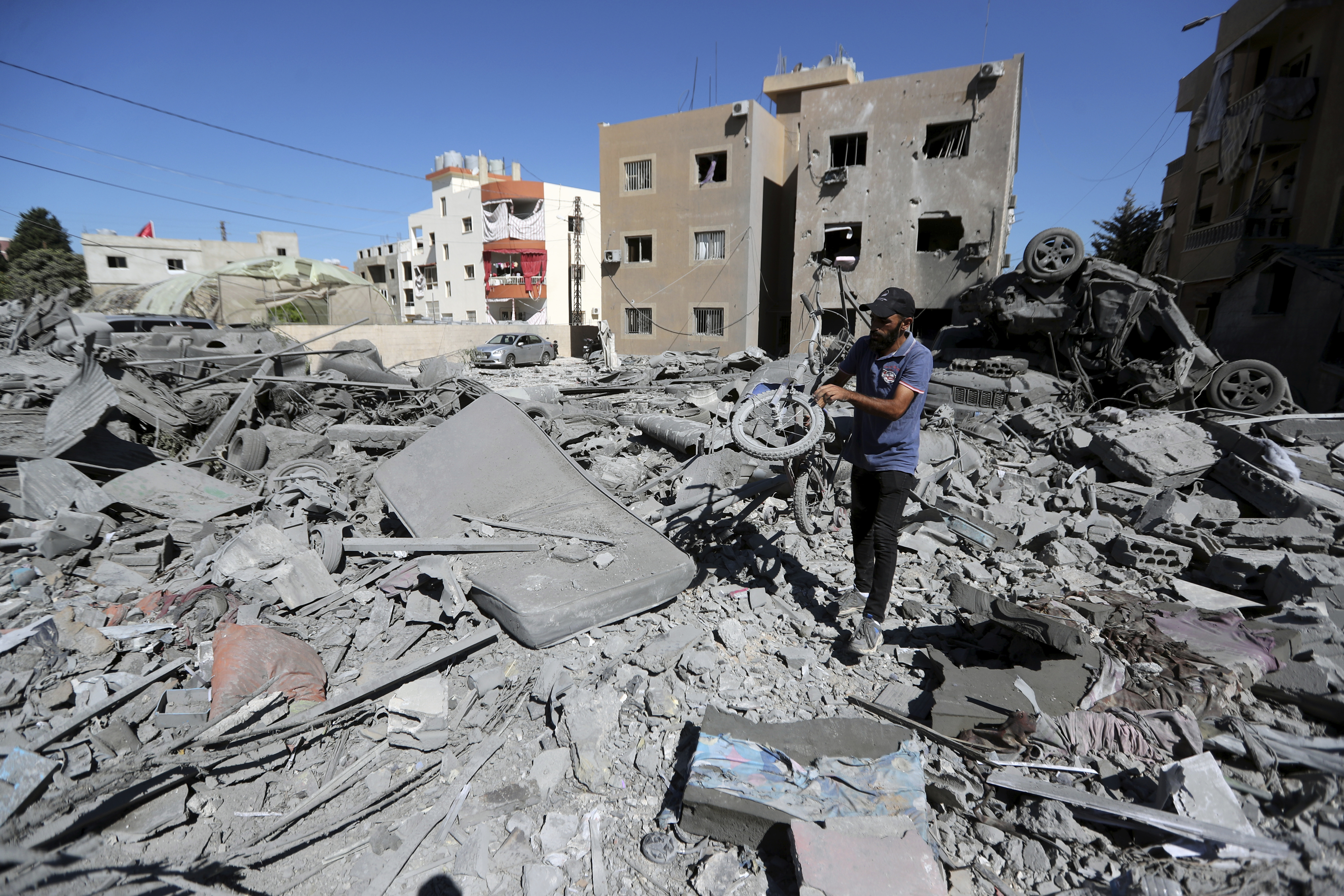 A man carries a damaged bicycle at the site of an Israeli airstrike in Saksakieh, south Lebanon, Thursday, Sept. 26, 2024. (AP Photo/Mohammed Zaatari)