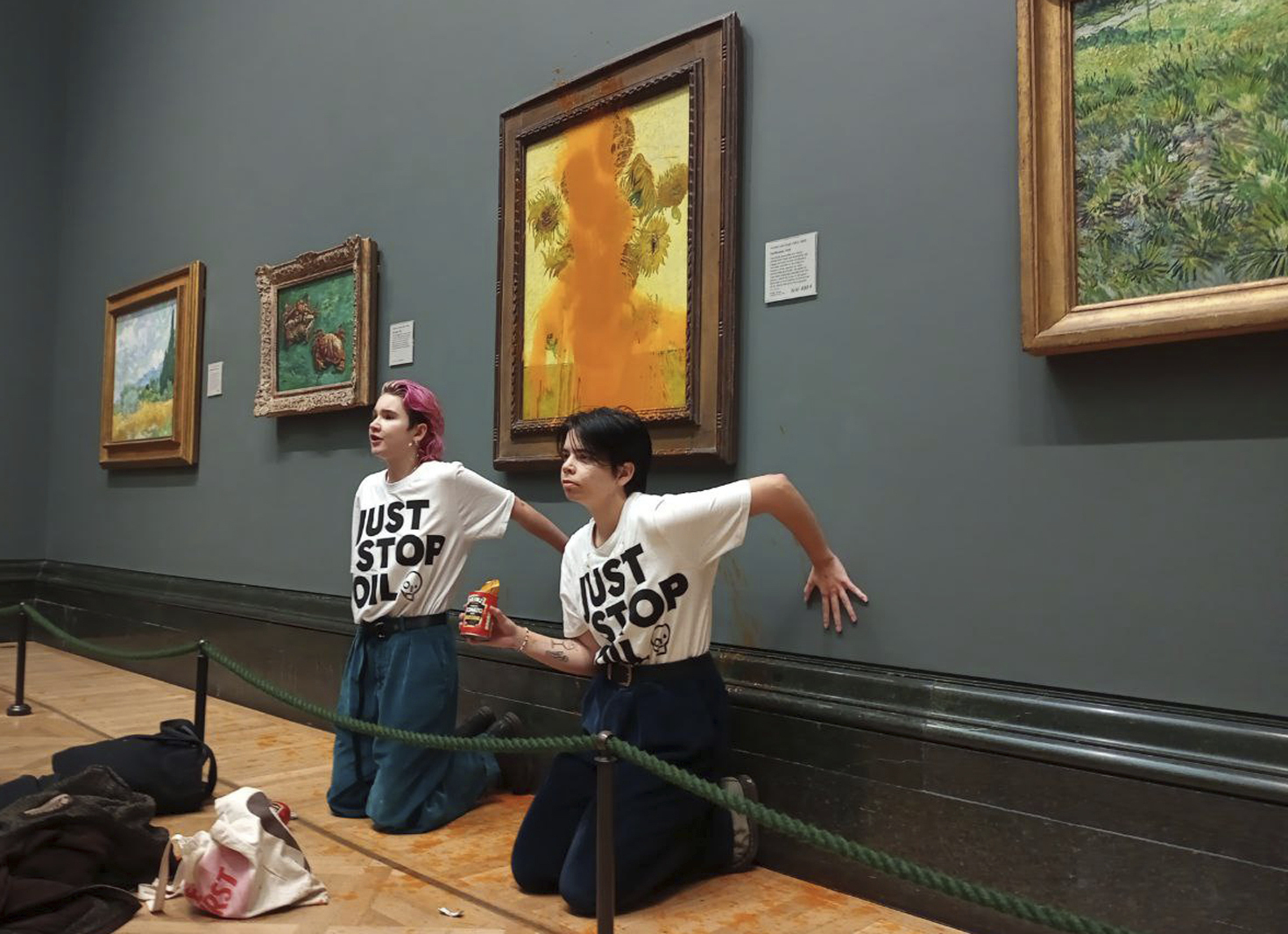 FILE - This photo provided by Just Stop Oil shows two protesters who have thrown tinned soup at Vincent Van Gogh's famous 1888 work Sunflowers at the National Gallery in London, Oct. 14, 2022. (Just Stop Oil via AP)