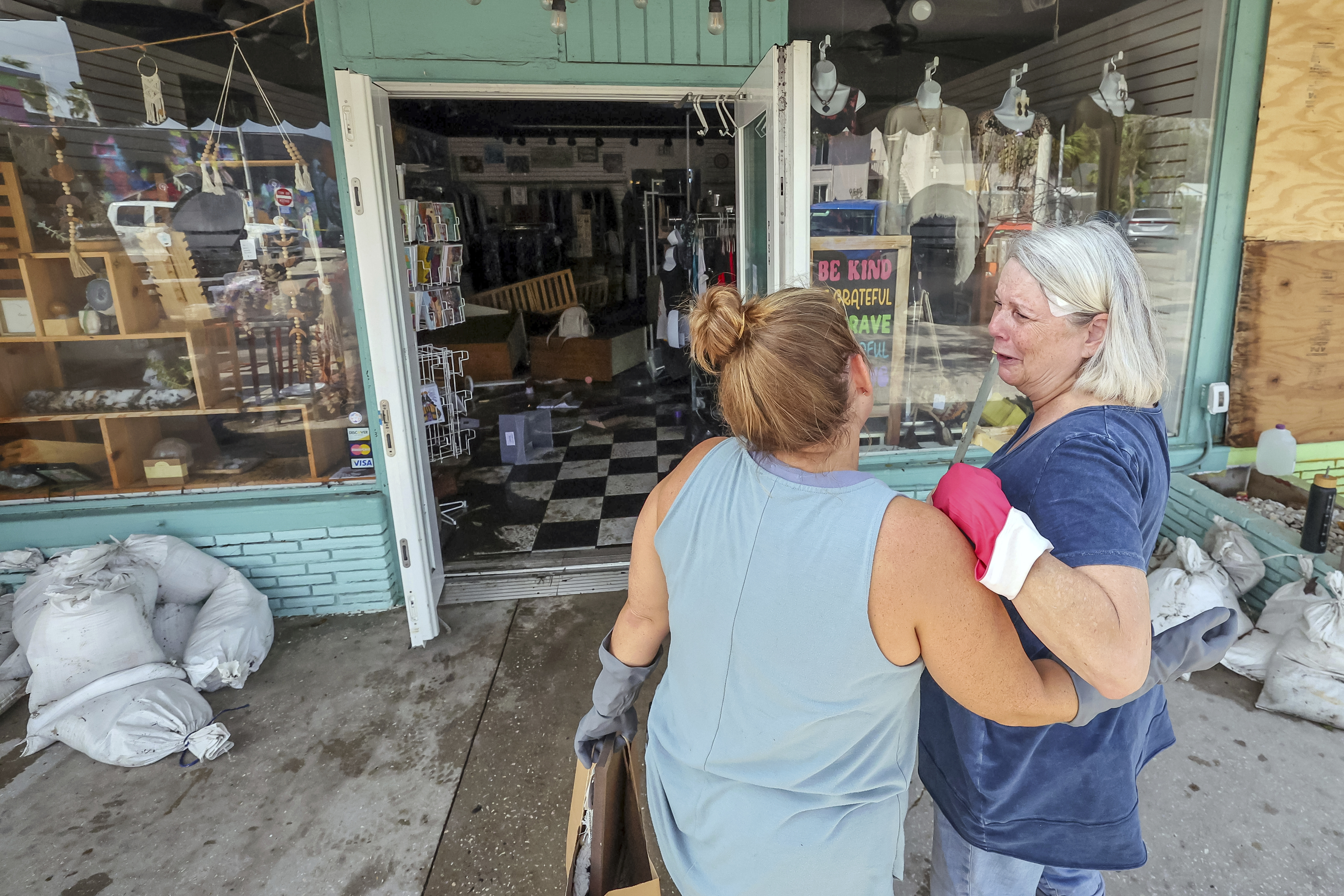 MJ Hodges, left, and her mother Jill Rice look at the damage caused to their store from the floodwaters of Hurricane Helene on Friday, Sept. 27, 2024, in Gulfport, Fla. (AP Photo/Mike Carlson)