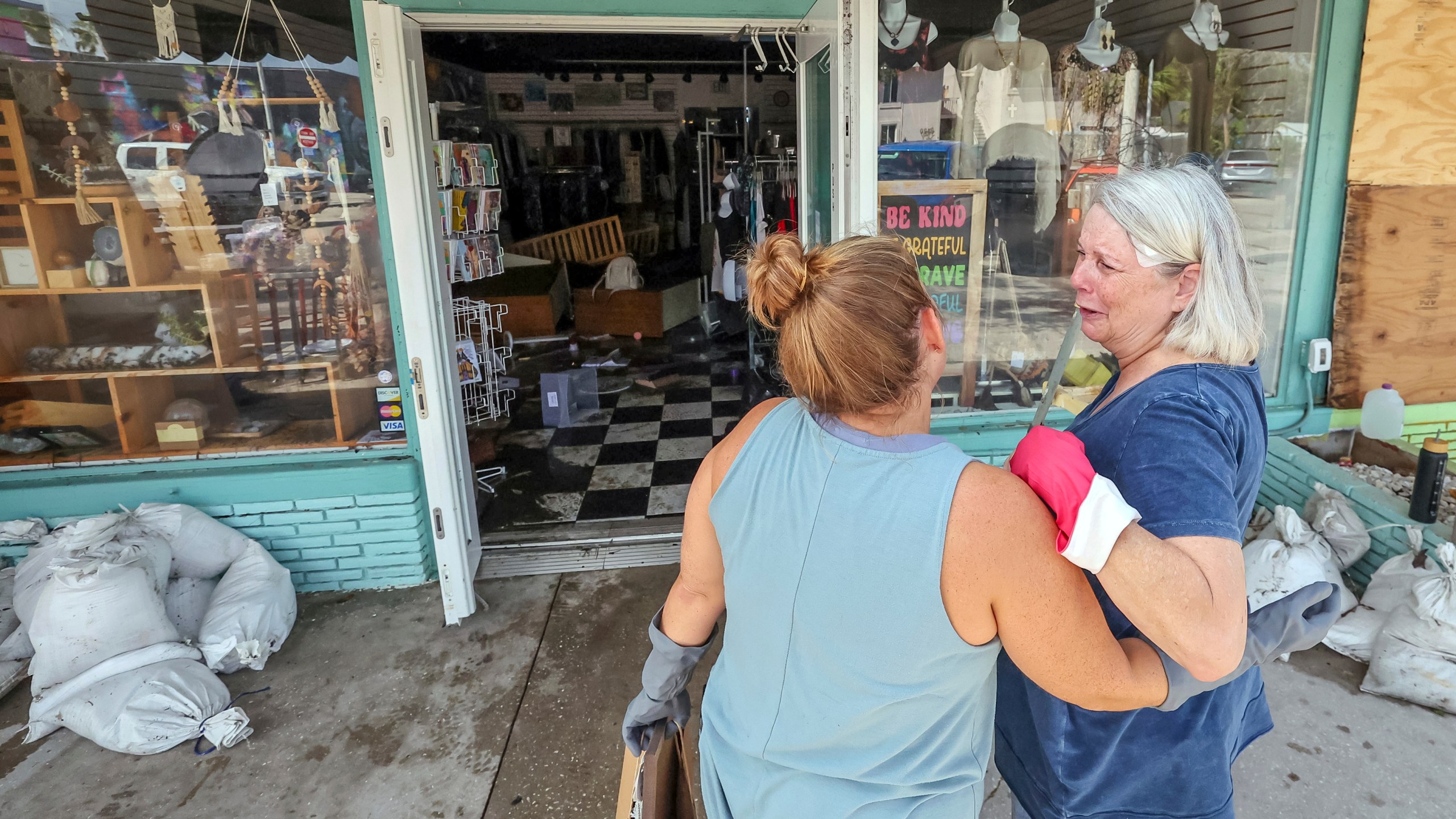 MJ Hodges, left, and her mother Jill Rice look at the damage caused to their store from the floodwaters of Hurricane Helene on Friday, Sept. 27, 2024, in Gulfport, Fla. (AP Photo/Mike Carlson)