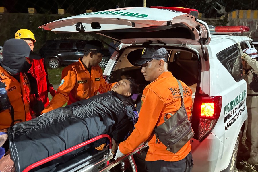 Rescuers transfer a survivor into an ambulance after a landslide set off by torrential rains smashed down into an unauthorized gold mining operation, killing several people, in Solok, West Sumatra, Indonesia, Saturday, Sept. 28, 2024. (AP Photo/John Nedy)