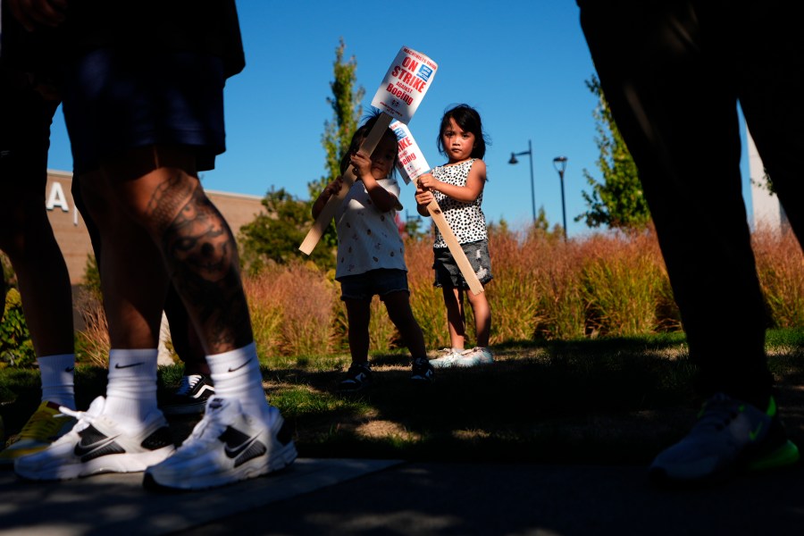 Accompanying their father, who works for Boeing, Kassie Odo 2, and Iya Odo, 4, hold small picket signs, Tuesday, Sept. 24, 2024, as Boeing workers strike near the company's factory in Renton, Wash. (AP Photo/Lindsey Wasson)