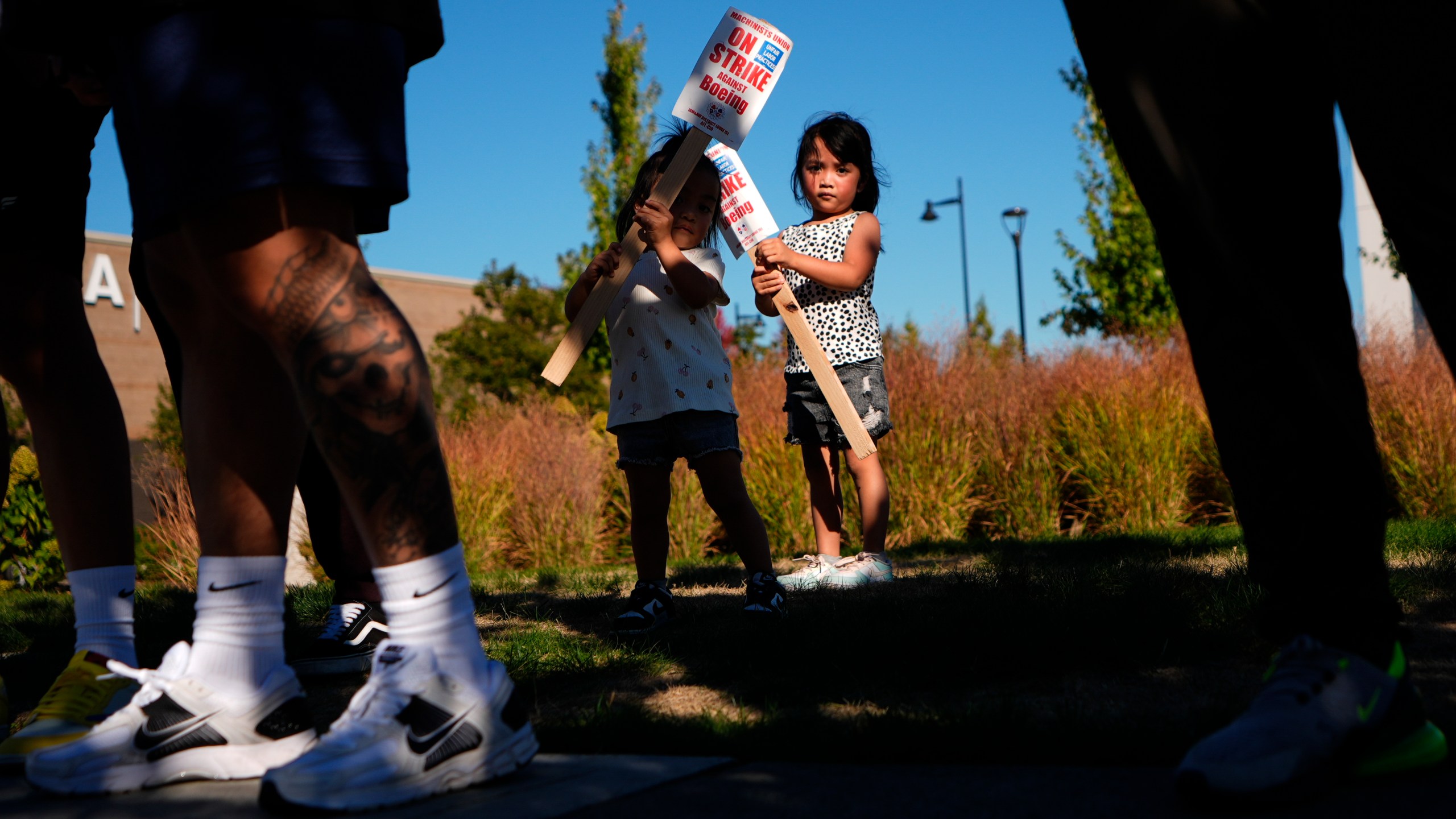 Accompanying their father, who works for Boeing, Kassie Odo 2, and Iya Odo, 4, hold small picket signs, Tuesday, Sept. 24, 2024, as Boeing workers strike near the company's factory in Renton, Wash. (AP Photo/Lindsey Wasson)