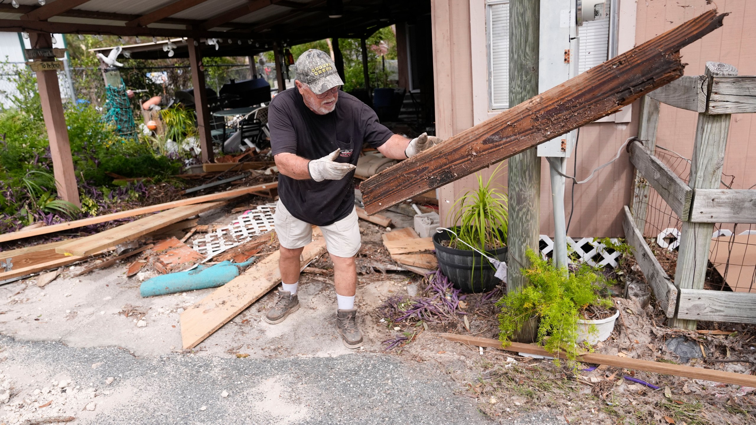 Dennis Johnson cleans out debris from his mother-in-law's heavily damaged home in the aftermath of Hurricane Helene, in Horseshoe Beach, Fla., Saturday, Sept. 28, 2024. (AP Photo/Gerald Herbert)