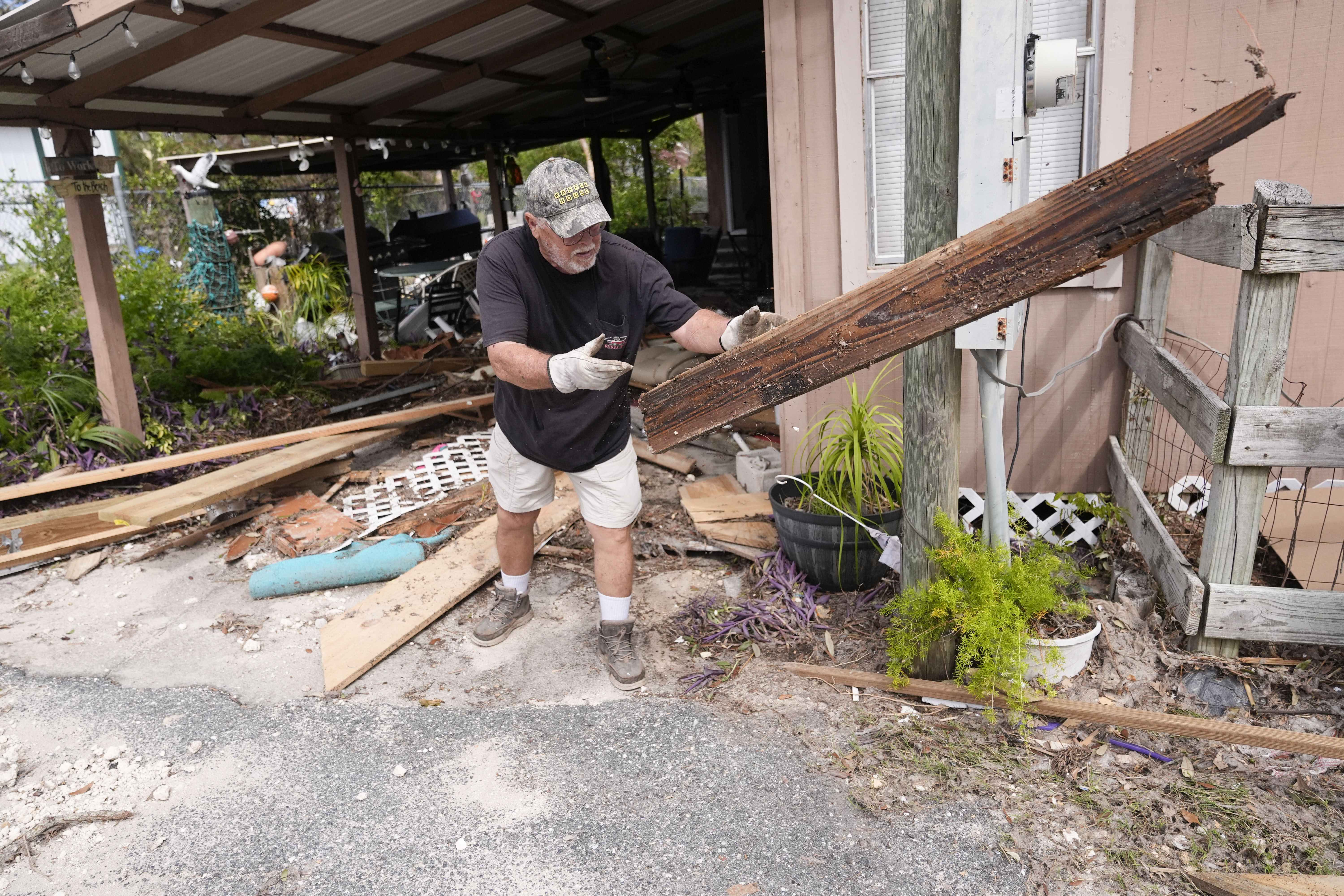 Dennis Johnson cleans out debris from his mother-in-law's heavily damaged home in the aftermath of Hurricane Helene, in Horseshoe Beach, Fla., Saturday, Sept. 28, 2024. (AP Photo/Gerald Herbert)