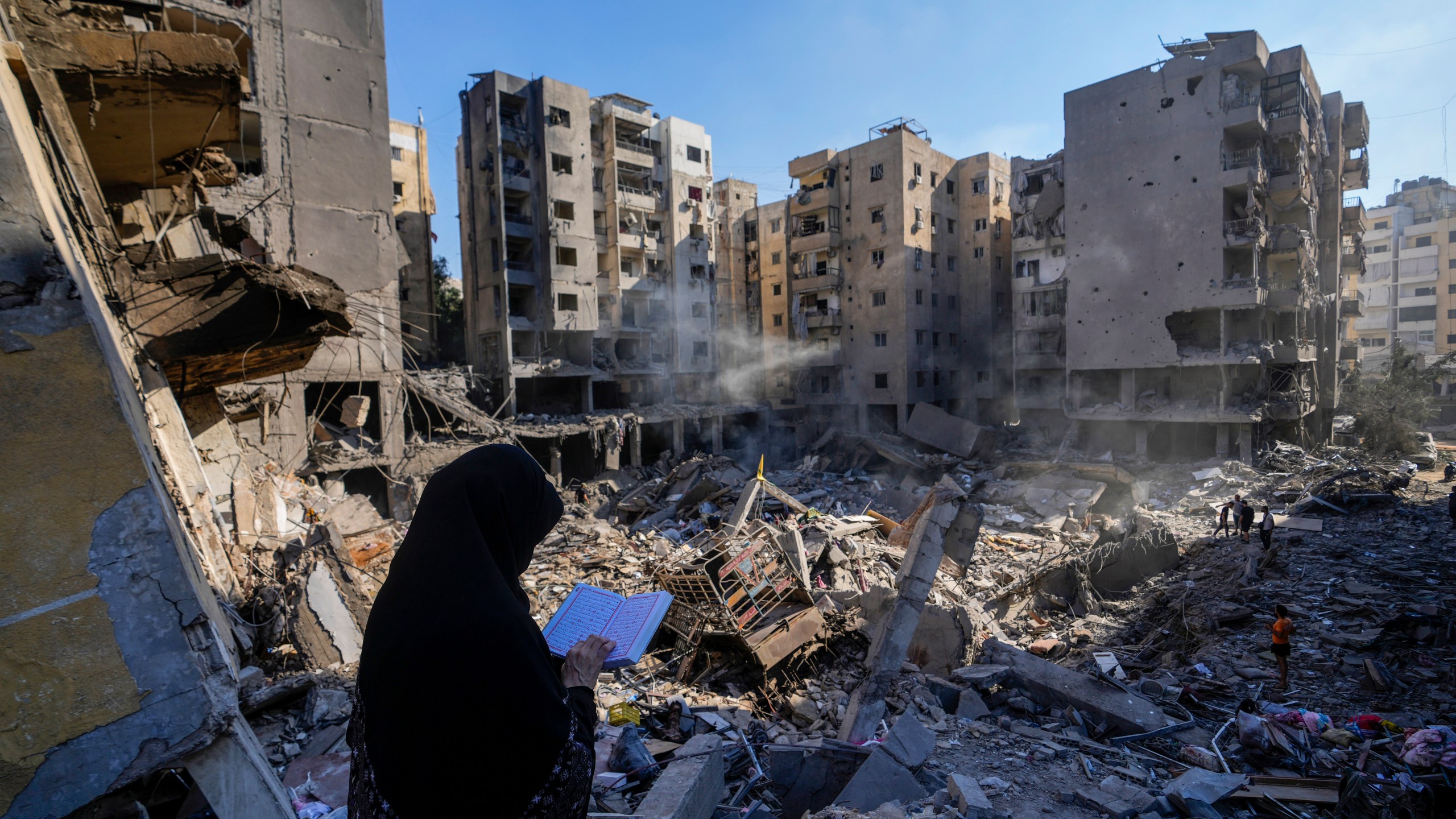 A woman reads the Quran at the site of the assassination of Hezbollah leader Hassan Nasrallah in Beirut's southern suburbs, Sunday, Sept. 29, 2024. (AP Photo/Hassan Ammar)