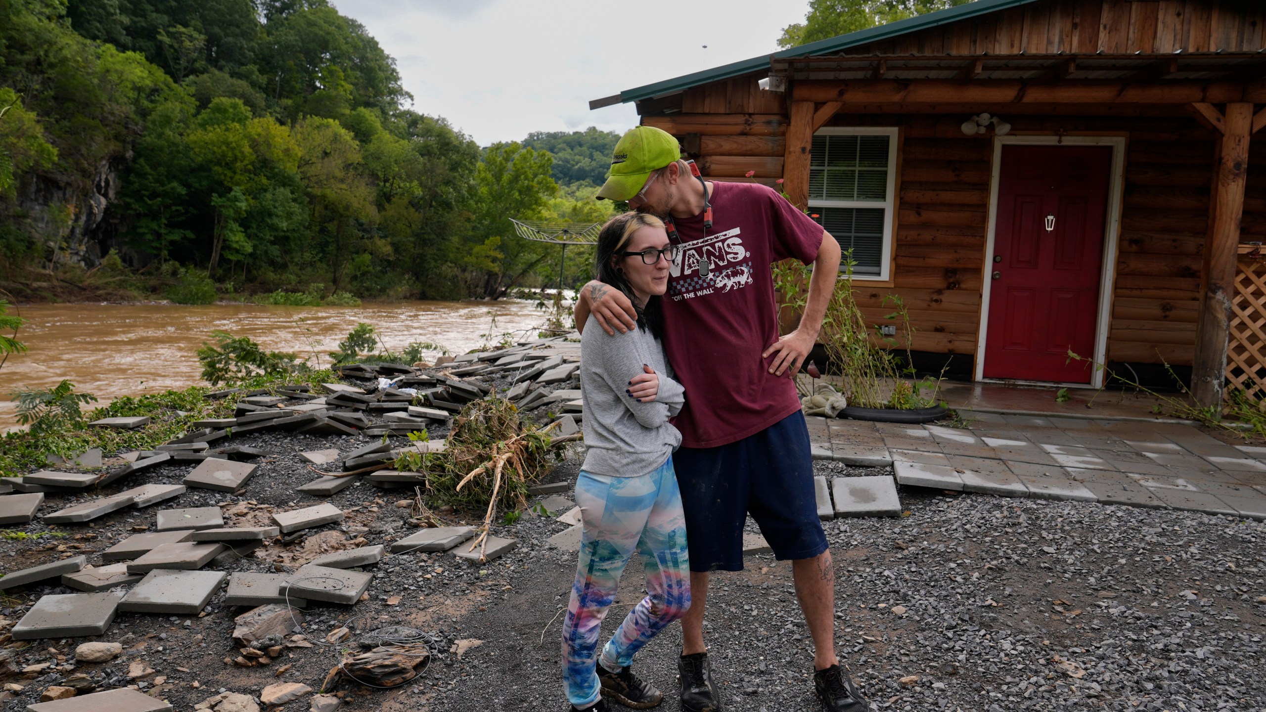 Jonah Wark, right, kisses his wife Sara Martin outside their flood-damaged home on the Pigeon River in the aftermath of Hurricane Helene, Saturday, Sept. 28, 2024, in Newport, Tenn. (AP Photo/George Walker IV)