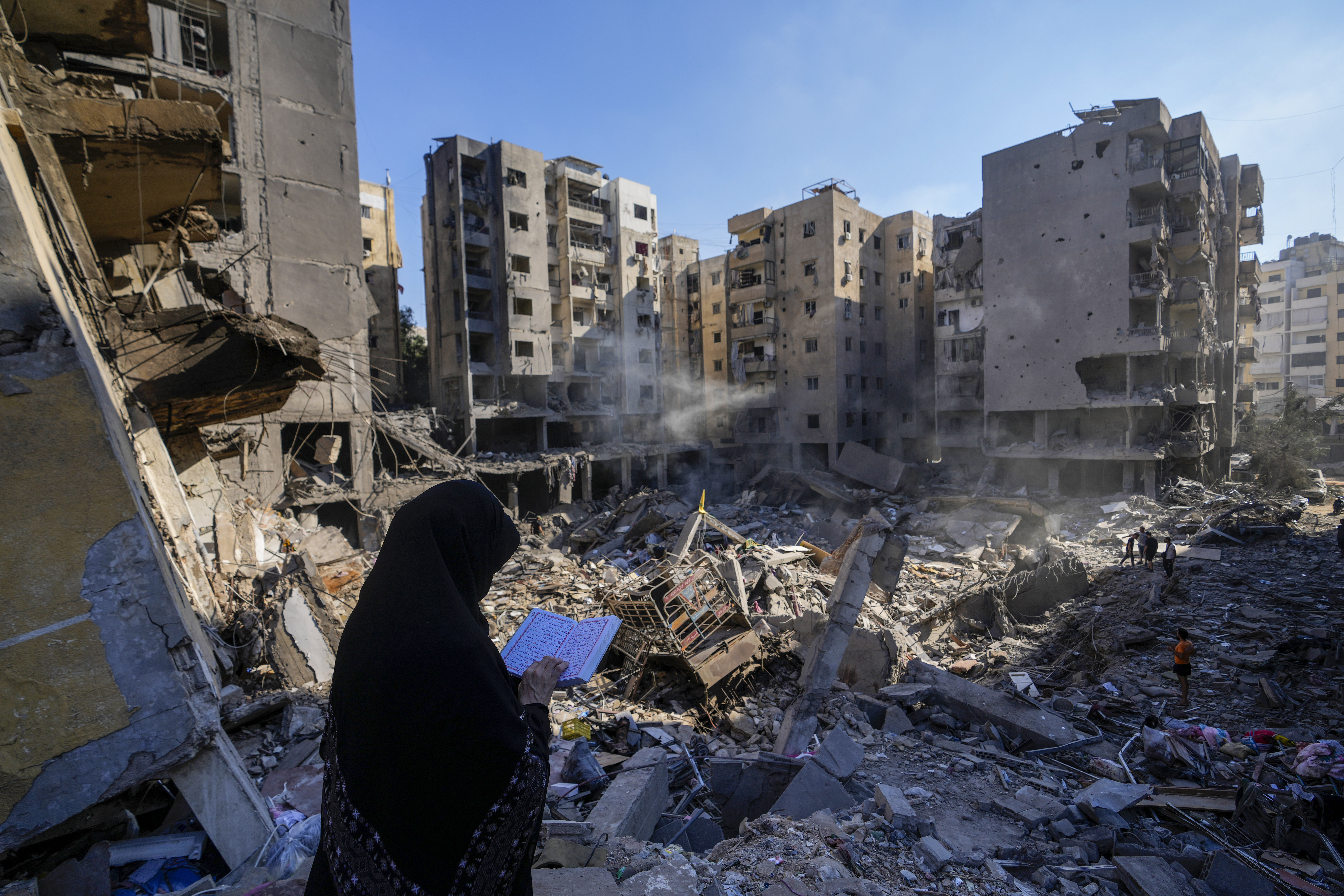 A woman reads the Quran at the site of the assassination of Hezbollah leader Hassan Nasrallah in Beirut's southern suburbs, Sunday, Sept. 29, 2024. (AP Photo/Hassan Ammar)