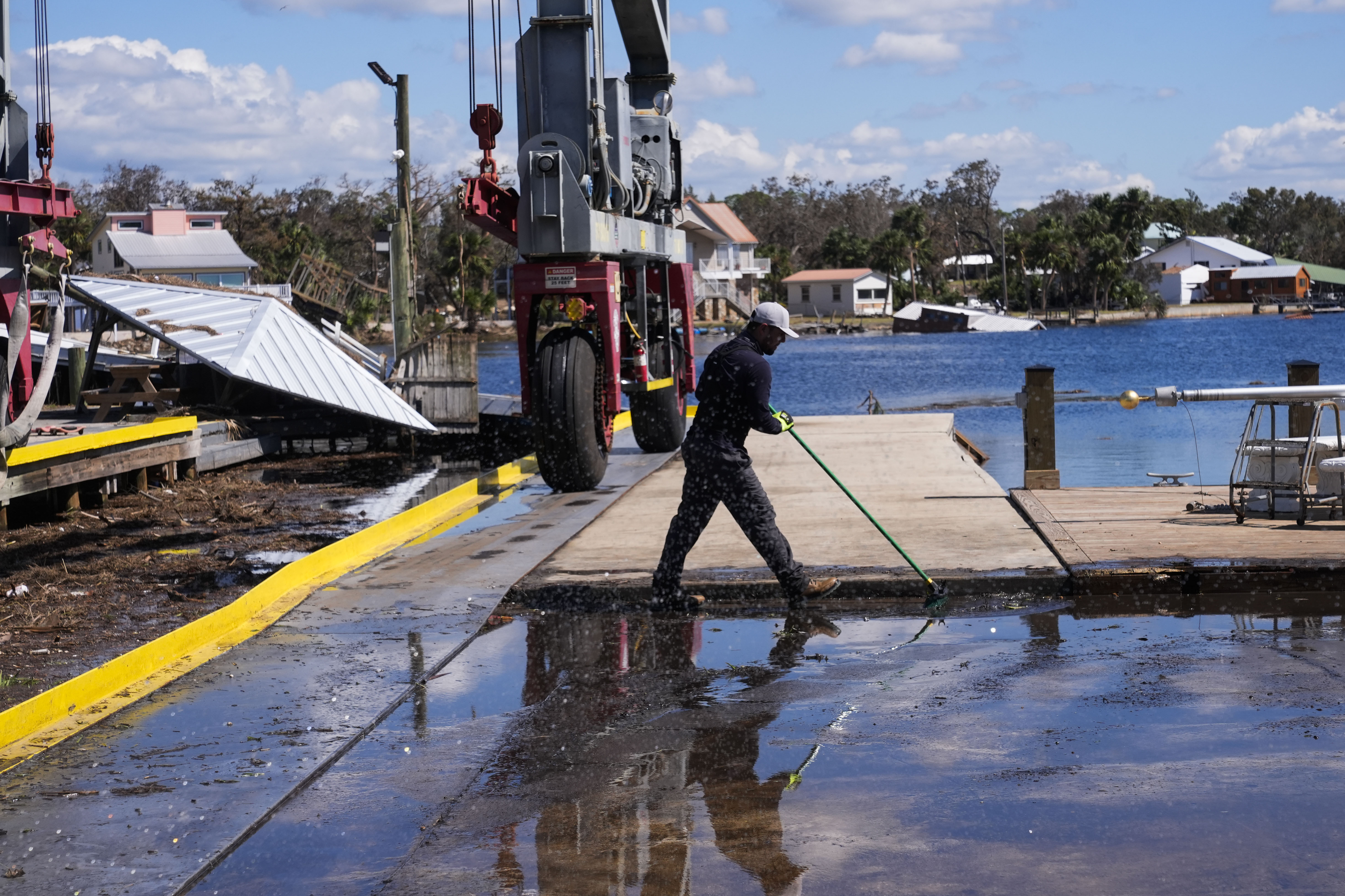 Workers clean up a dock where a boat shed was destroyed in the aftermath of Hurricane Helene, in Jena, Fla., Sunday, Sept. 29, 2024. (AP Photo/Gerald Herbert)