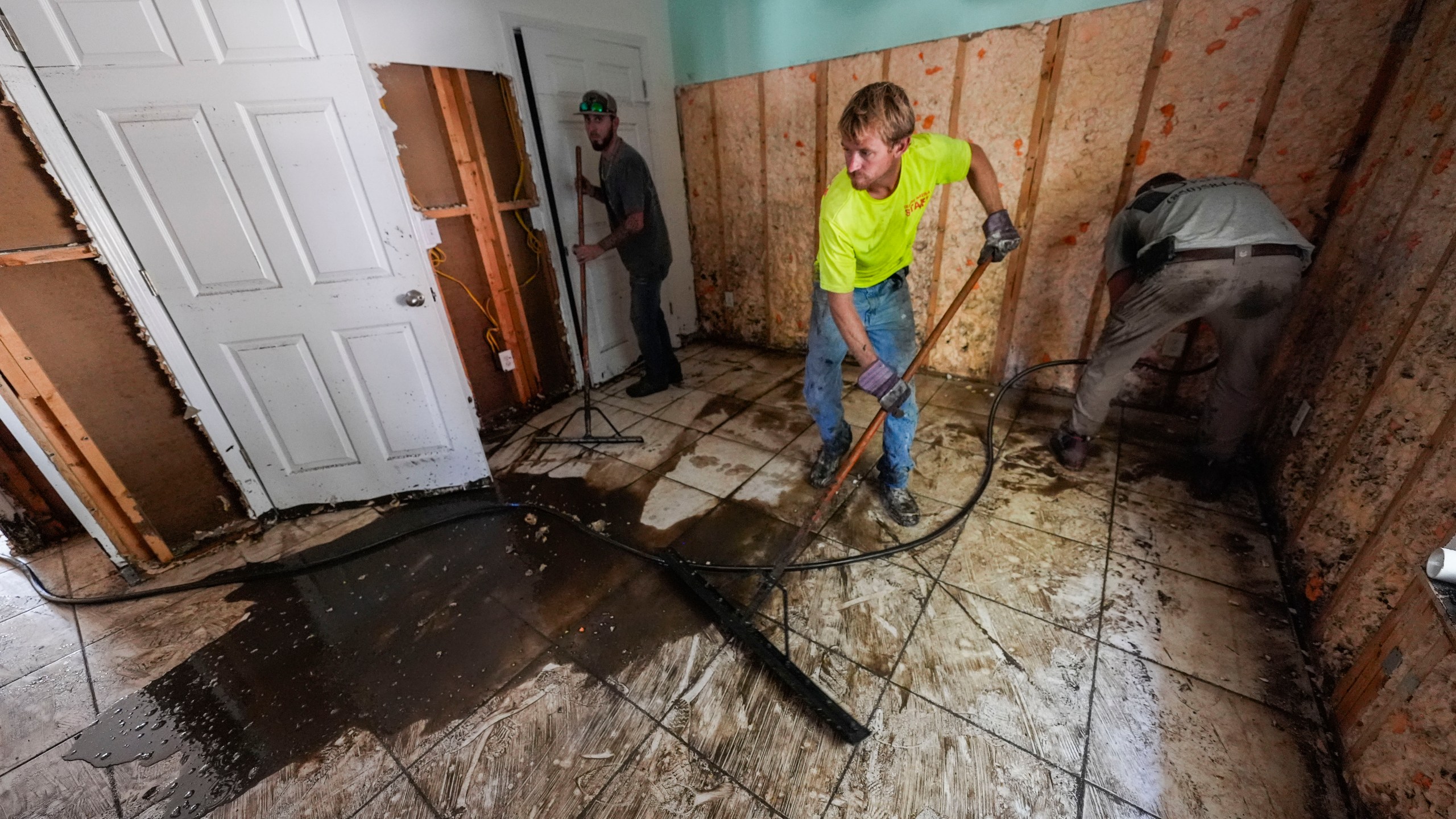 Workers clean and gut a property that was flooded from the storm surge, in the aftermath of Hurricane Helene, in Steinhatchee, Fla., Sunday, Sept. 29, 2024. (AP Photo/Gerald Herbert)