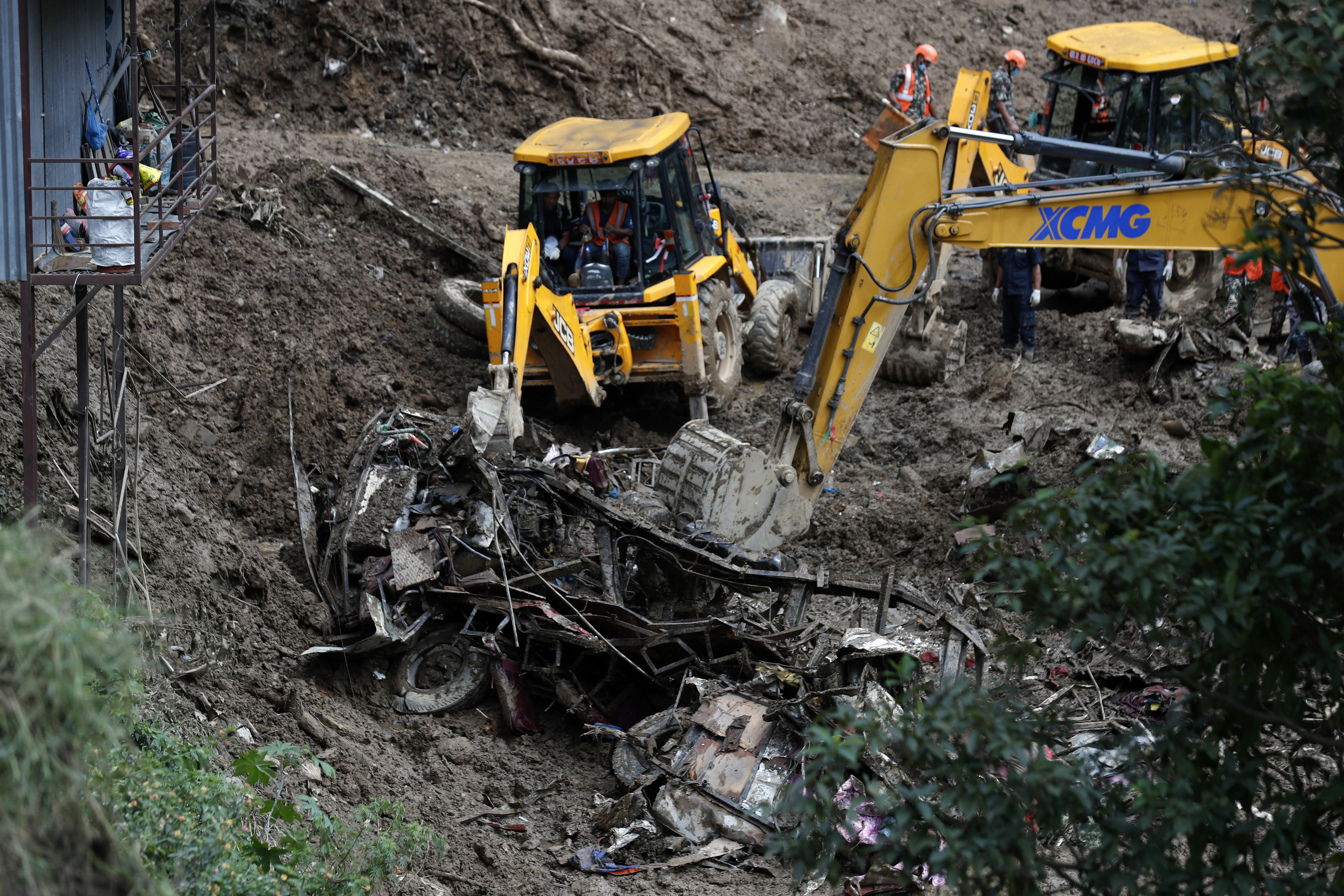 Earthmovers remove mangled automobile debris from a landslide caused by heavy rains in Kathmandu, Nepal, Sunday, Sept. 29, 2024. (AP Photo/Sujan Gurung)