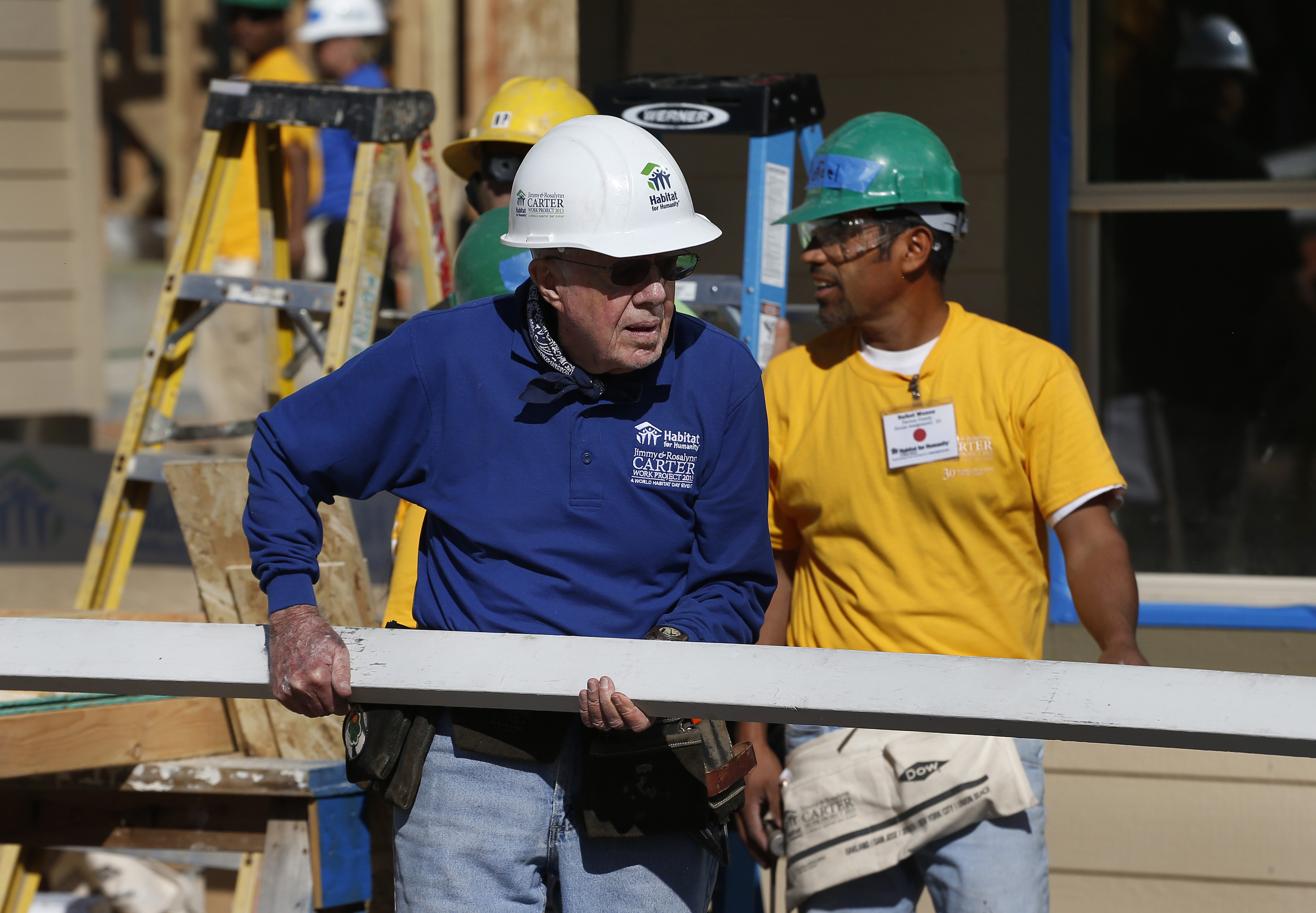 FILE - Former President Jimmy Carter helps cut wood for home construction at a Habitat for Humanity construction site in the Globeville neighborhood of Denver, Wednesday Oct. 9, 2013. (AP Photo/Brennan Linsley, File)