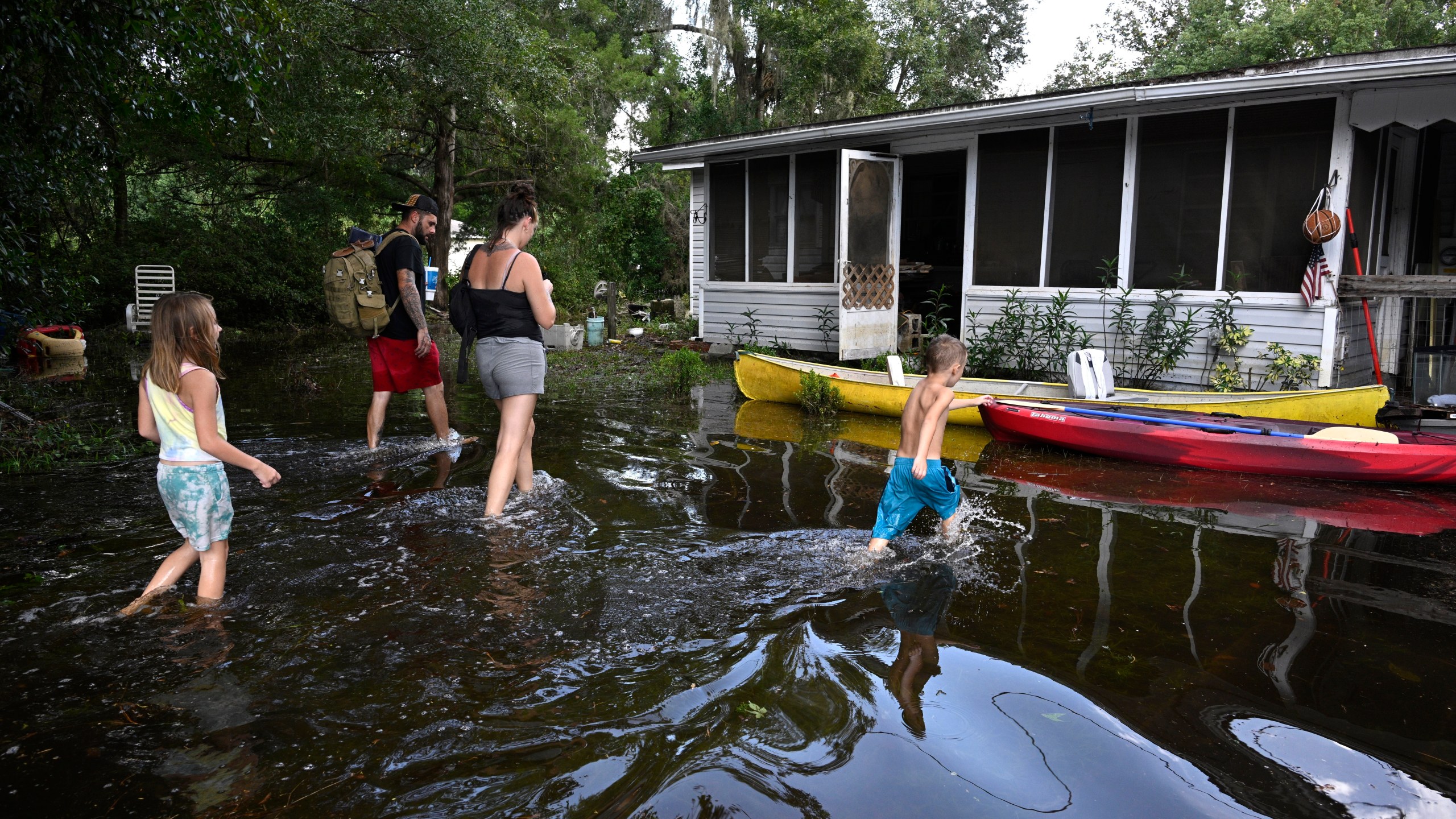 FILE - Dustin Holmes, rear, his girlfriend Hailey Morgan, and her children Aria Skye Hall, 7, left, and Kyle Ross, 4, right, arrive to their flooded home in the aftermath of Hurricane Helene, Sept. 27, 2024, in Crystal River, Fla. (AP Photo/Phelan M. Ebenhack, File)