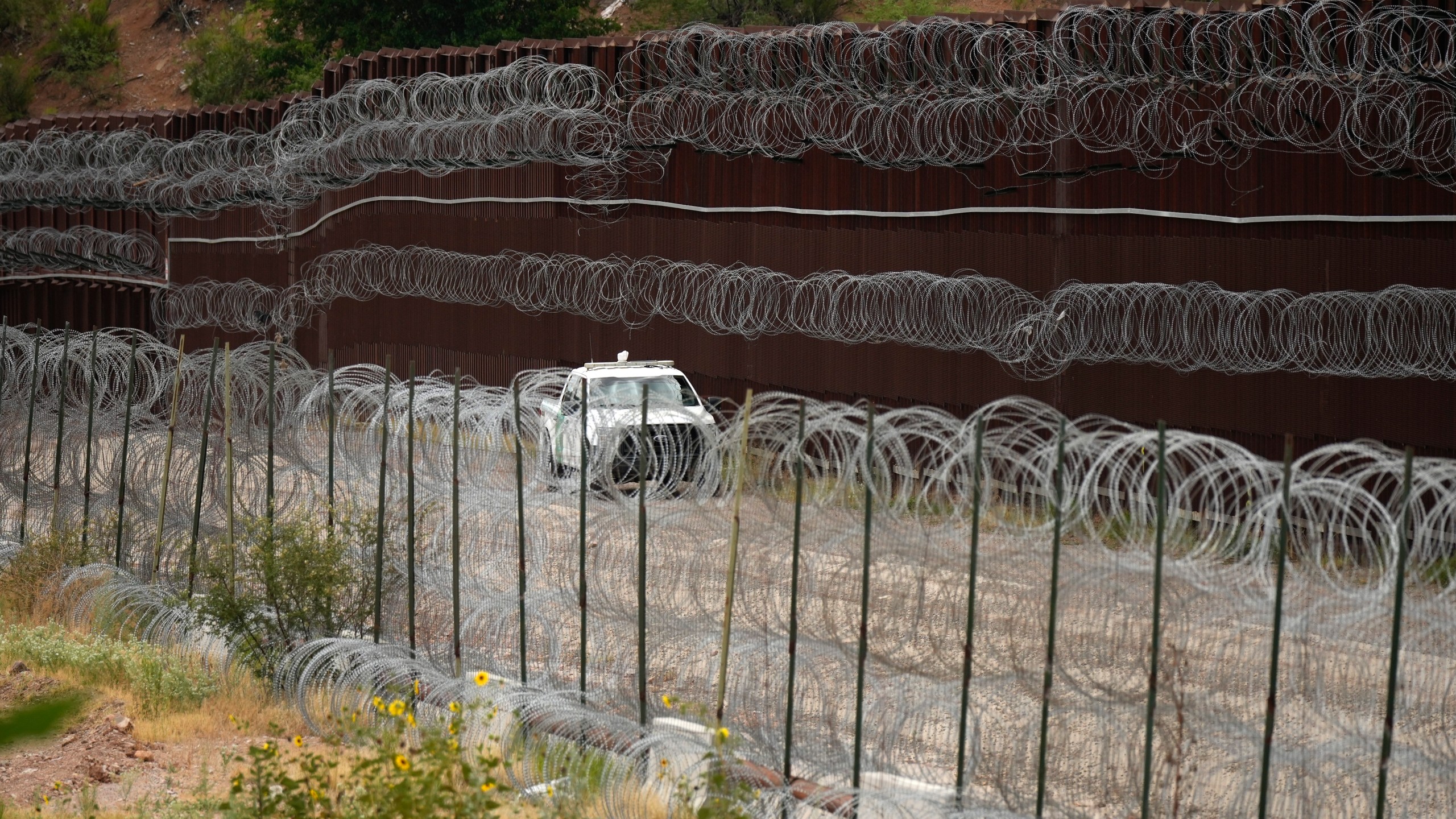 FILE - A vehicle drives along the U.S. side of the US-Mexico border wall in Nogales, Ariz., June 25, 2024. The Biden administration is making asylum restrictions at the southern border even tougher. The changes come in the middle of an election campaign where border security is a key concern for voters, and the administration is increasingly eager to show voters it's taking a hard stance. (AP Photo/Jae C. Hong, Pool, File)