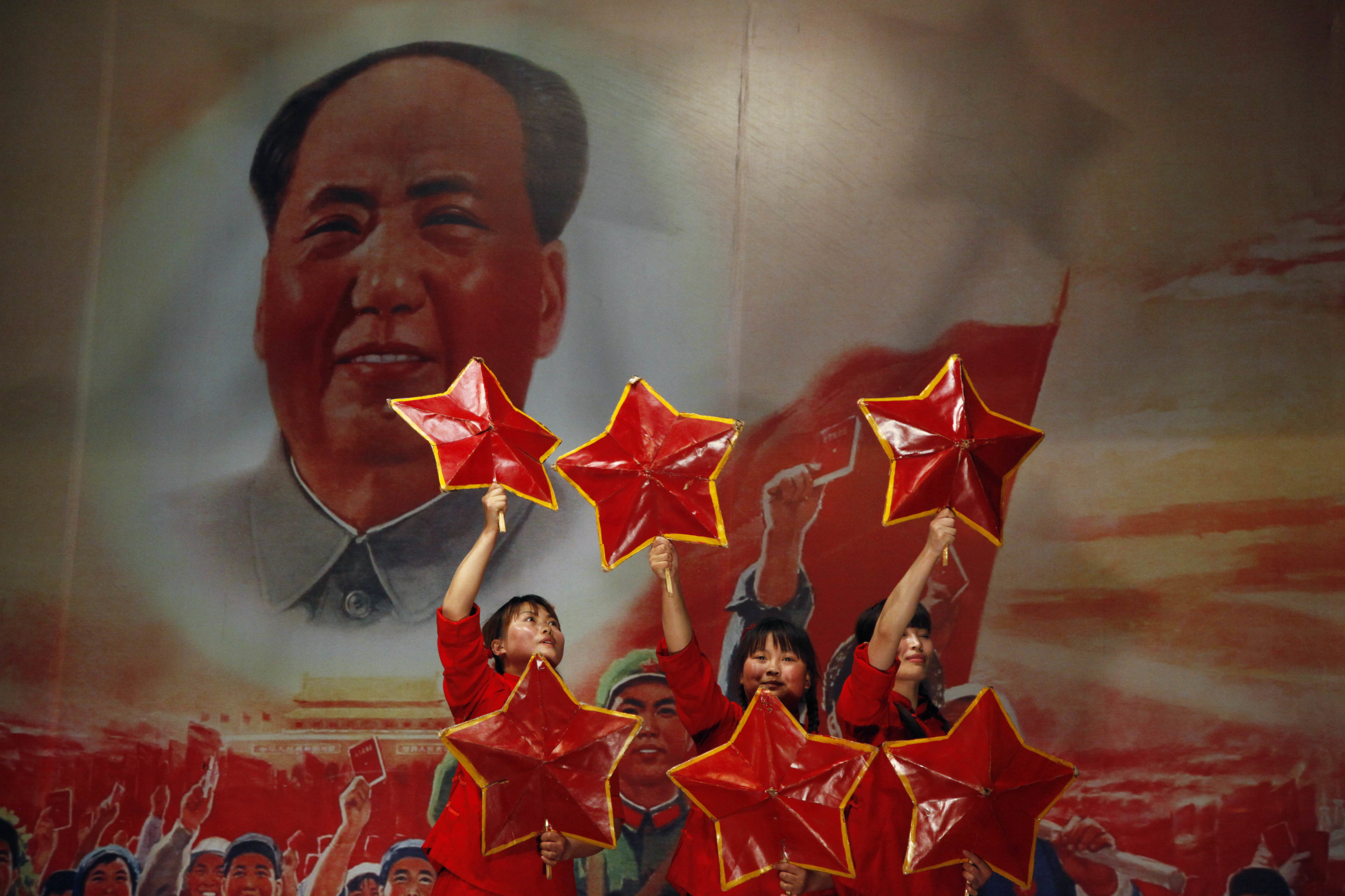 FILE - Performers take to the stage near a picture of Mao Zedong at the Red Classic restaurant that capitalizes on nostalgia for China's past in Beijing, May 2, 2011. (AP Photo/Ng Han Guan, File)