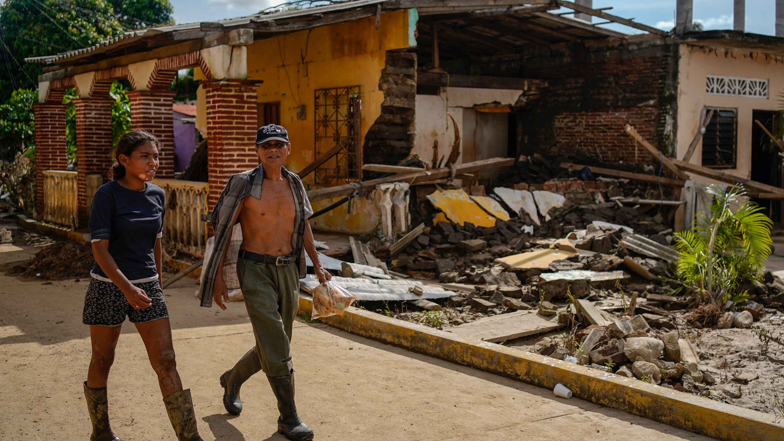 Residents walk past a house damaged by Hurricane John in Coyuca de Benitez, Guerrero state, Mexico, Monday, Sept. 30, 2024. (AP Photo/Felix Marquez)