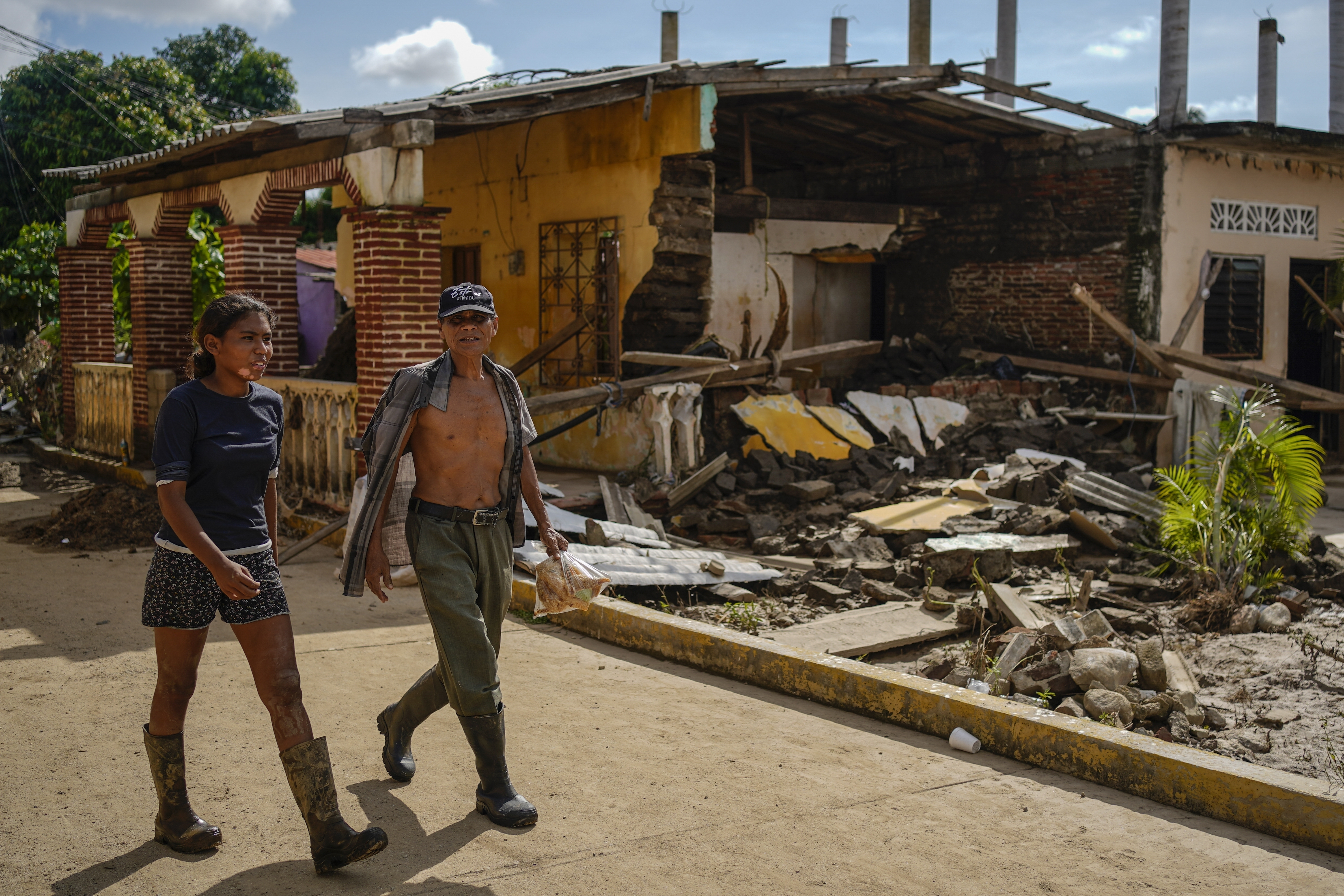 Residents walk past a house damaged by Hurricane John in Coyuca de Benitez, Guerrero state, Mexico, Monday, Sept. 30, 2024. (AP Photo/Felix Marquez)