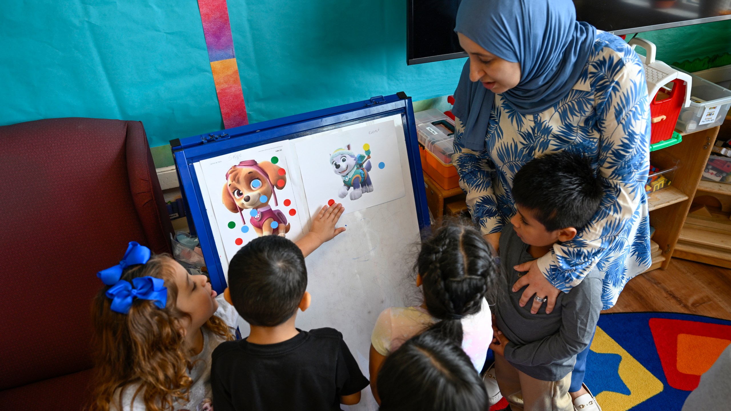 Preschool teacher Tinhinane Meziane, right, watches her students discuss the results on voting the most popular character of the TV show PAW Patrol at the ACCA Child Development Center, Thursday, Sept. 19, 2024, in Annandale, Va. The students are getting foundational lessons on how to live in a democracy by allowing them to regularly vote on different things through out the day. (AP Photo/John McDonnell)