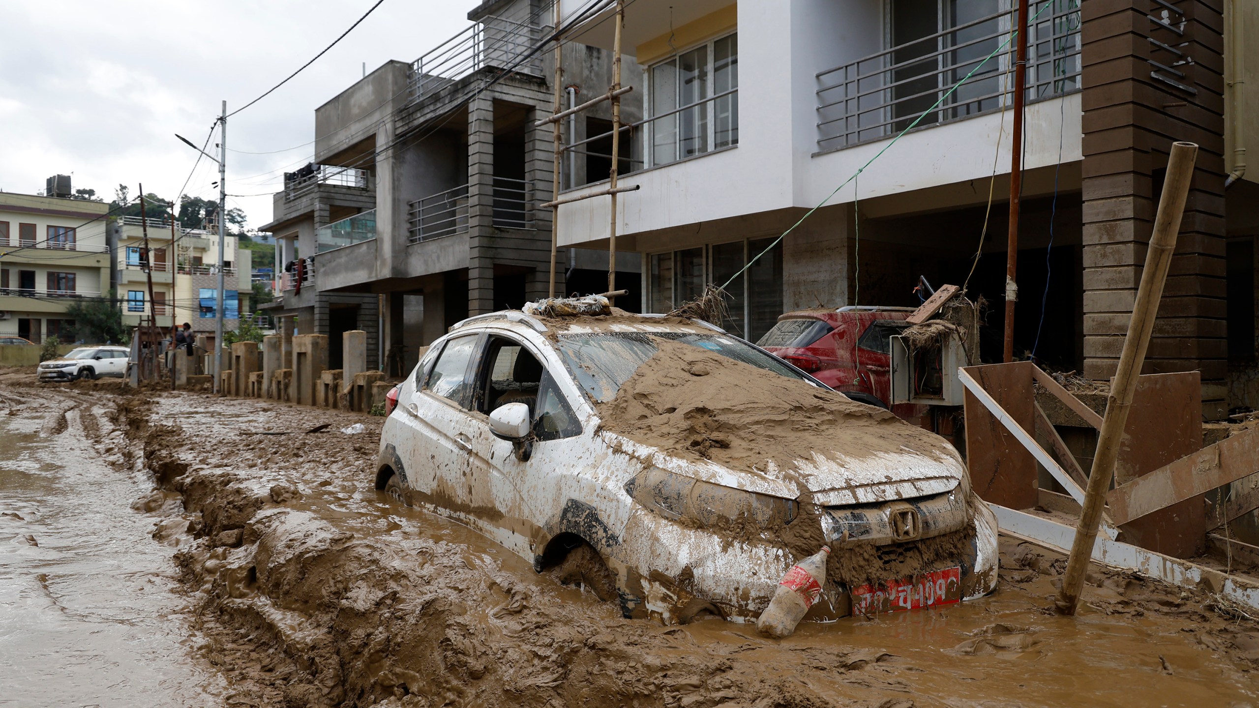 A car parked outside a building is swamped in mud in Kathmandu, Nepal, Monday, Sept. 30, 2024 in the aftermath of a flood caused by heavy rains. (AP Photo/Gopen Rai)