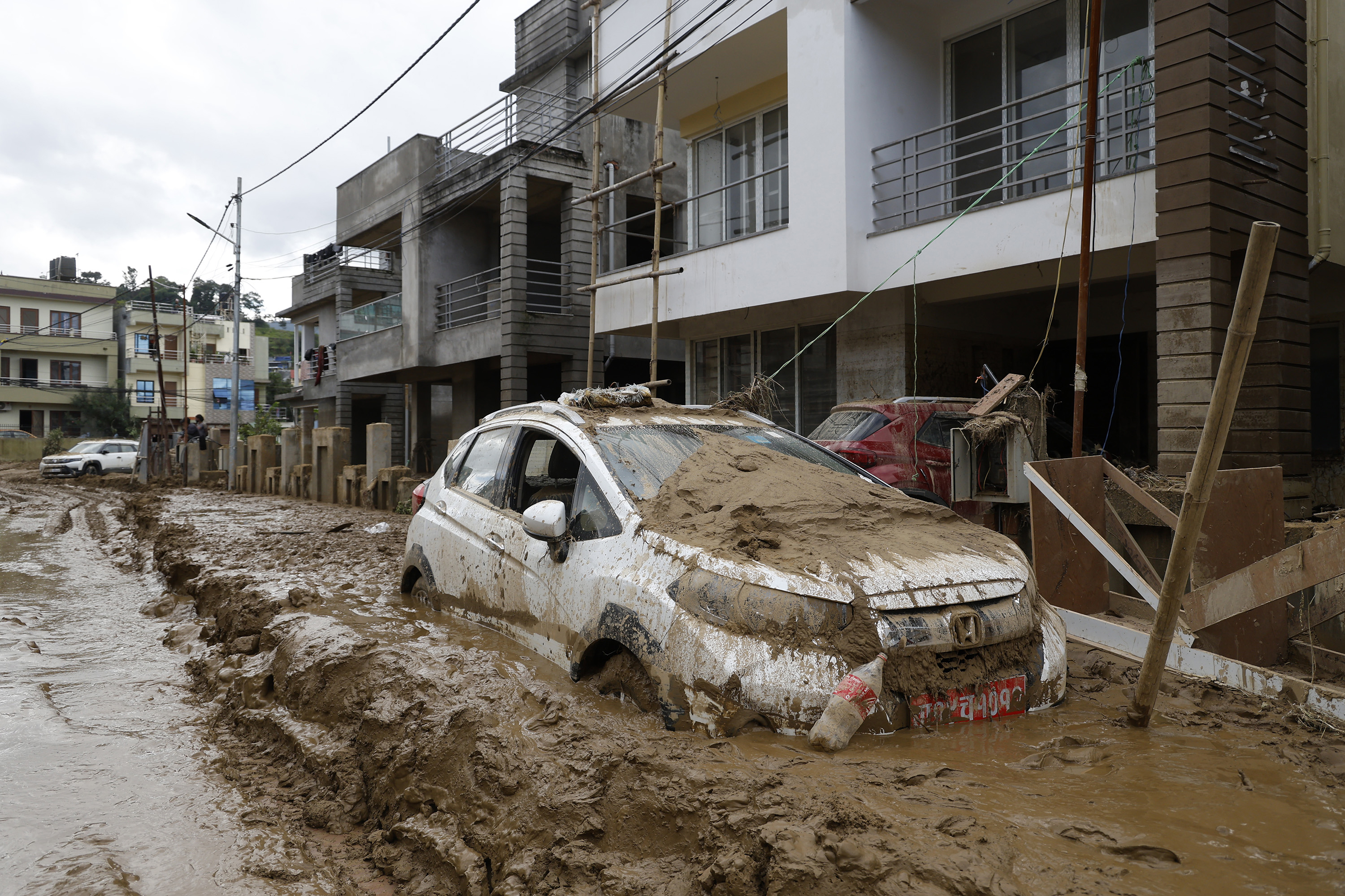 A car parked outside a building is swamped in mud in Kathmandu, Nepal, Monday, Sept. 30, 2024 in the aftermath of a flood caused by heavy rains. (AP Photo/Gopen Rai)