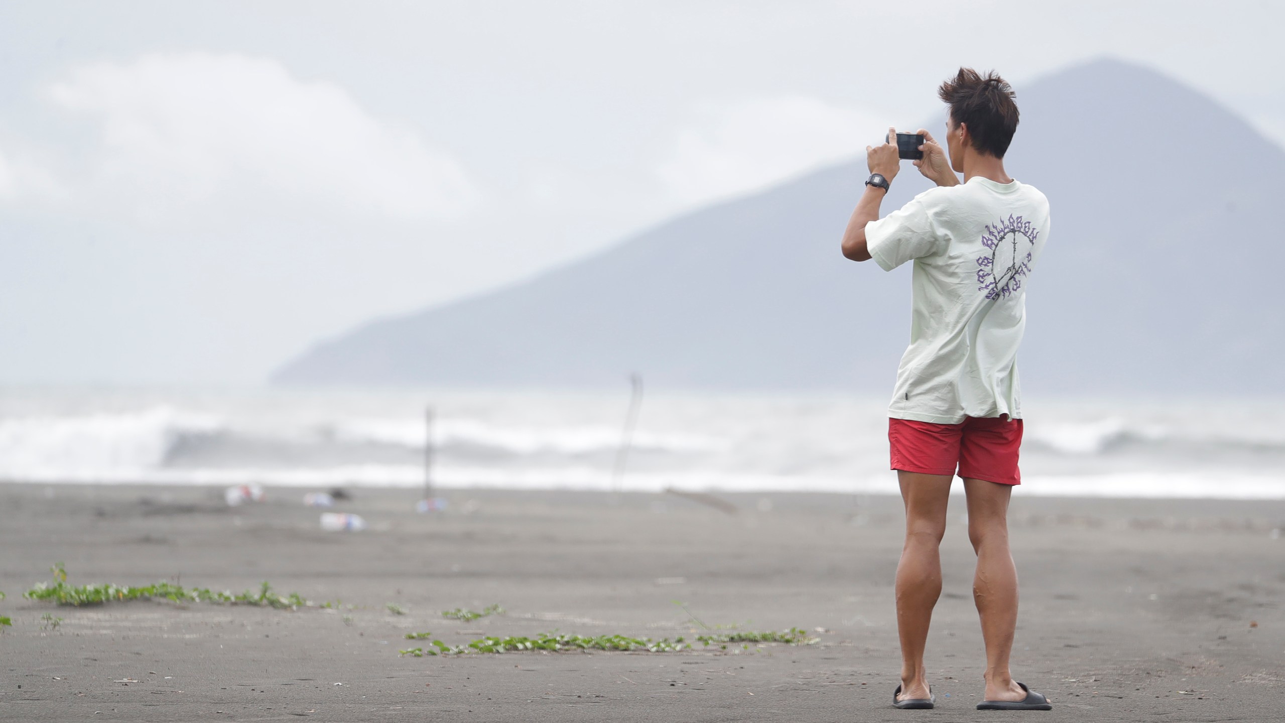 A man takes a photo on a beach as Typhoon Krathon approaches to Taiwan in Yilan County, eastern coast of Taiwan, Tuesday, Oct. 1, 2024. (AP Photo/Chiang Ying-ying)