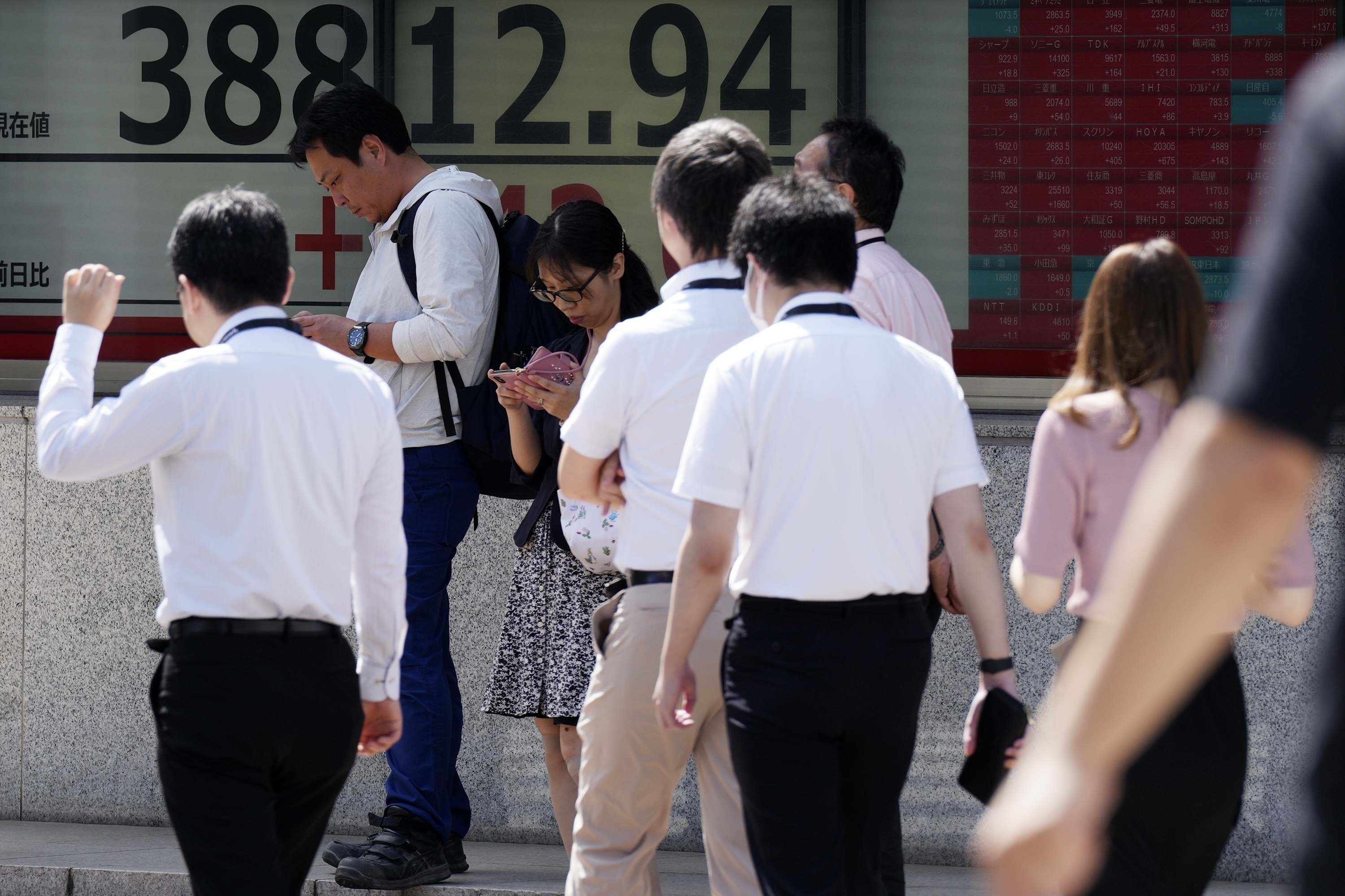 FILE - People walk in front of an electronic stock board showing Japan's Nikkei index at a securities firm Thursday, Sept. 26, 2024, in Tokyo. (AP Photo/Eugene Hoshiko, File)