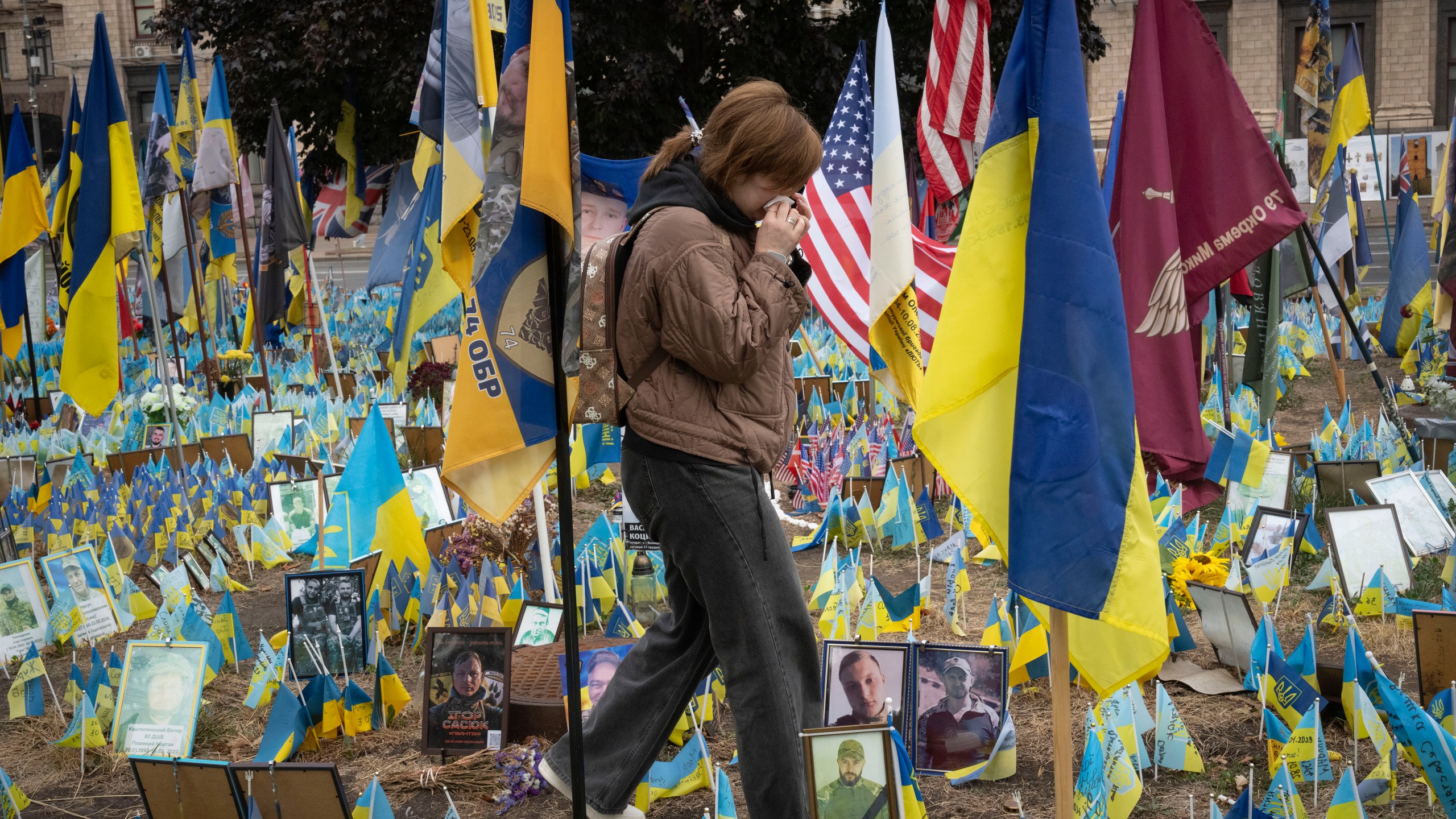 People react during a nationwide minute of silence in memory of fallen soldiers, who defended their homeland in war with Russia, on Defenders Day at the improvised war memorial in Independence square in Kyiv, Ukraine, Tuesday, Oct. 1, 2024. (AP Photo/Efrem Lukatsky)