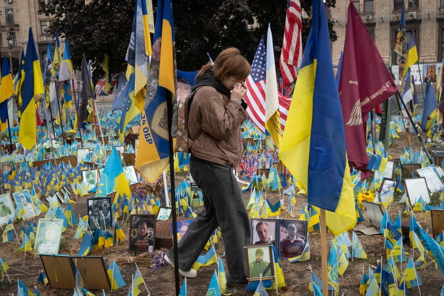 People react during a nationwide minute of silence in memory of fallen soldiers, who defended their homeland in war with Russia, on Defenders Day at the improvised war memorial in Independence square in Kyiv, Ukraine, Tuesday, Oct. 1, 2024. (AP Photo/Efrem Lukatsky)