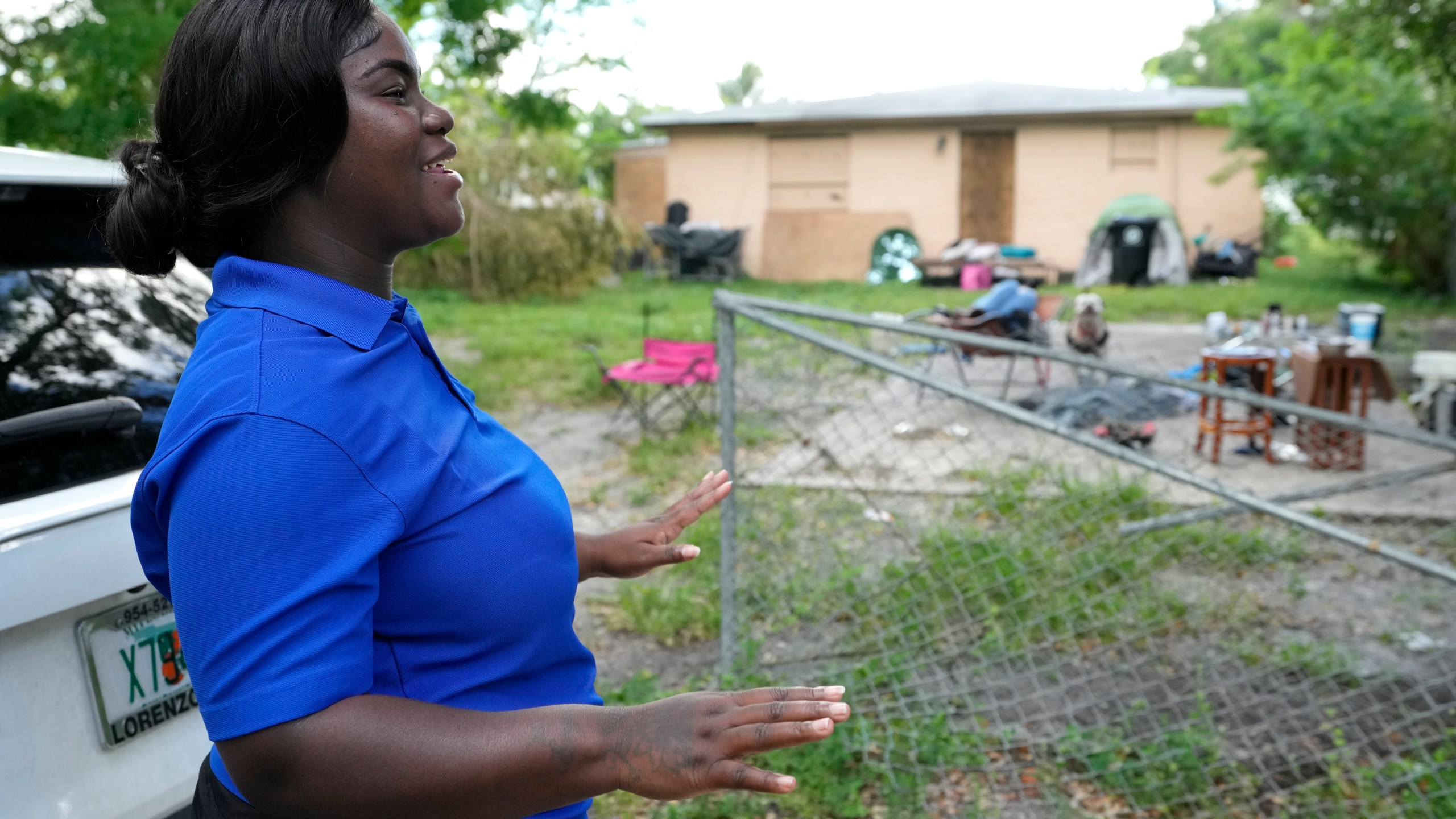 Erica Dorsett, program director of the TaskForce Fore Ending Homelessness, speaks with homeless people near an abandoned home on the first day of a statute that took effect, making it illegal in Florida to sleep on sidewalks, in parks, on beaches or in other public spaces — one of the country's strictest anti-homelessness laws, Tuesday, Oct. 1, 2024, in Fort Lauderdale, Fla. (AP Photo/Lynne Sladky)